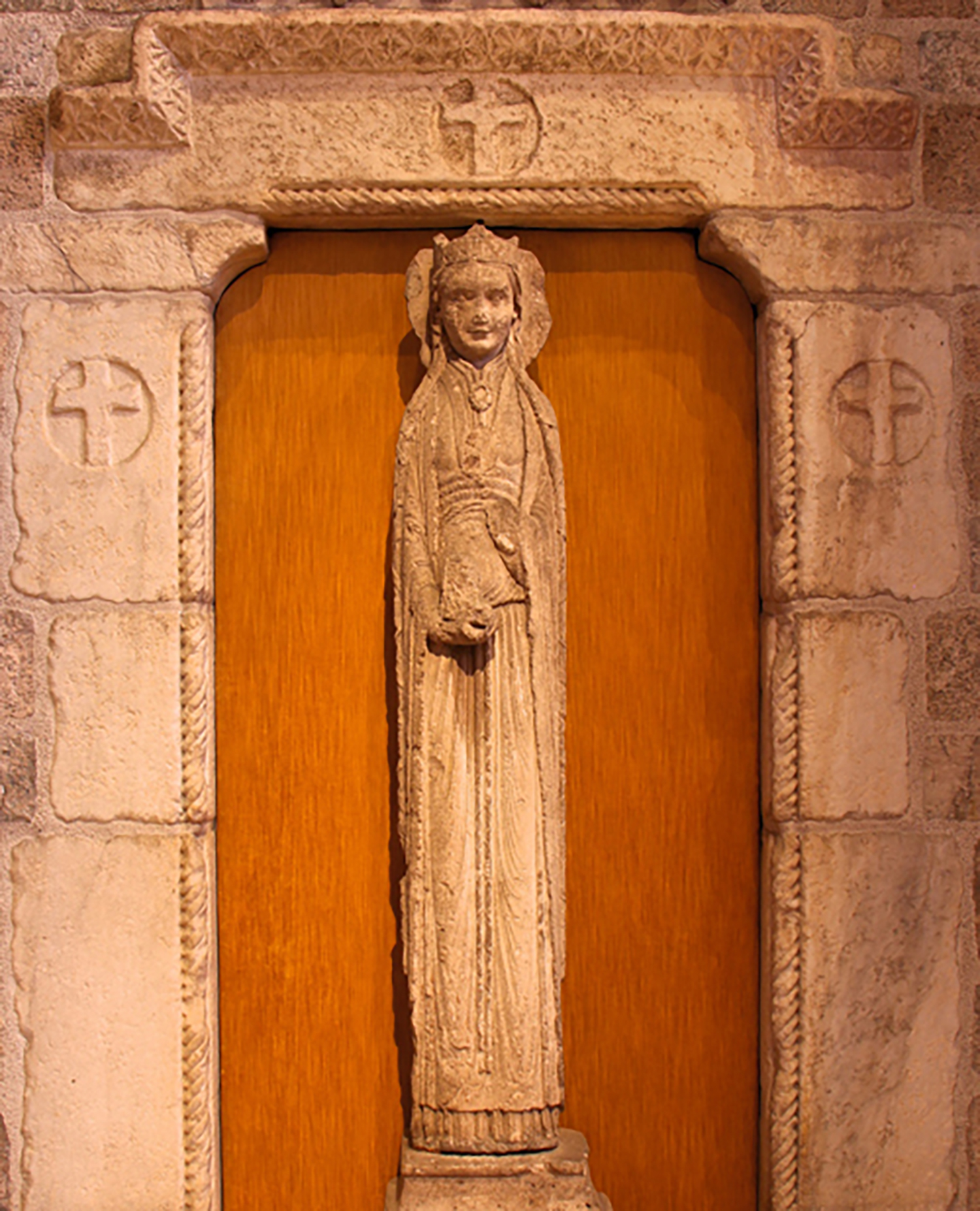 Figure 9: Affectionately called the “Slim Princess” by the Pitcairn family, this 12th-century limestone statue column of a haloed queen is installed in the great hall of Glencairn, enclosed by a stone portal with crosses.
