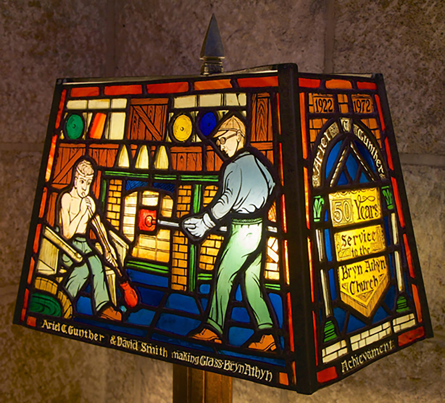 Figure 10: This lamp was given to Ariel Gunther after 50 years of service. Gunther (right) was in charge of constructing glass furnaces, the chemical composition of the glass batches, and the overall supervision of the factory. David Smith (left), the primary glassblower, came to Bryn Athyn in 1922. This lamp can be seen beside the reception desk at Bryn Athyn Cathedral.