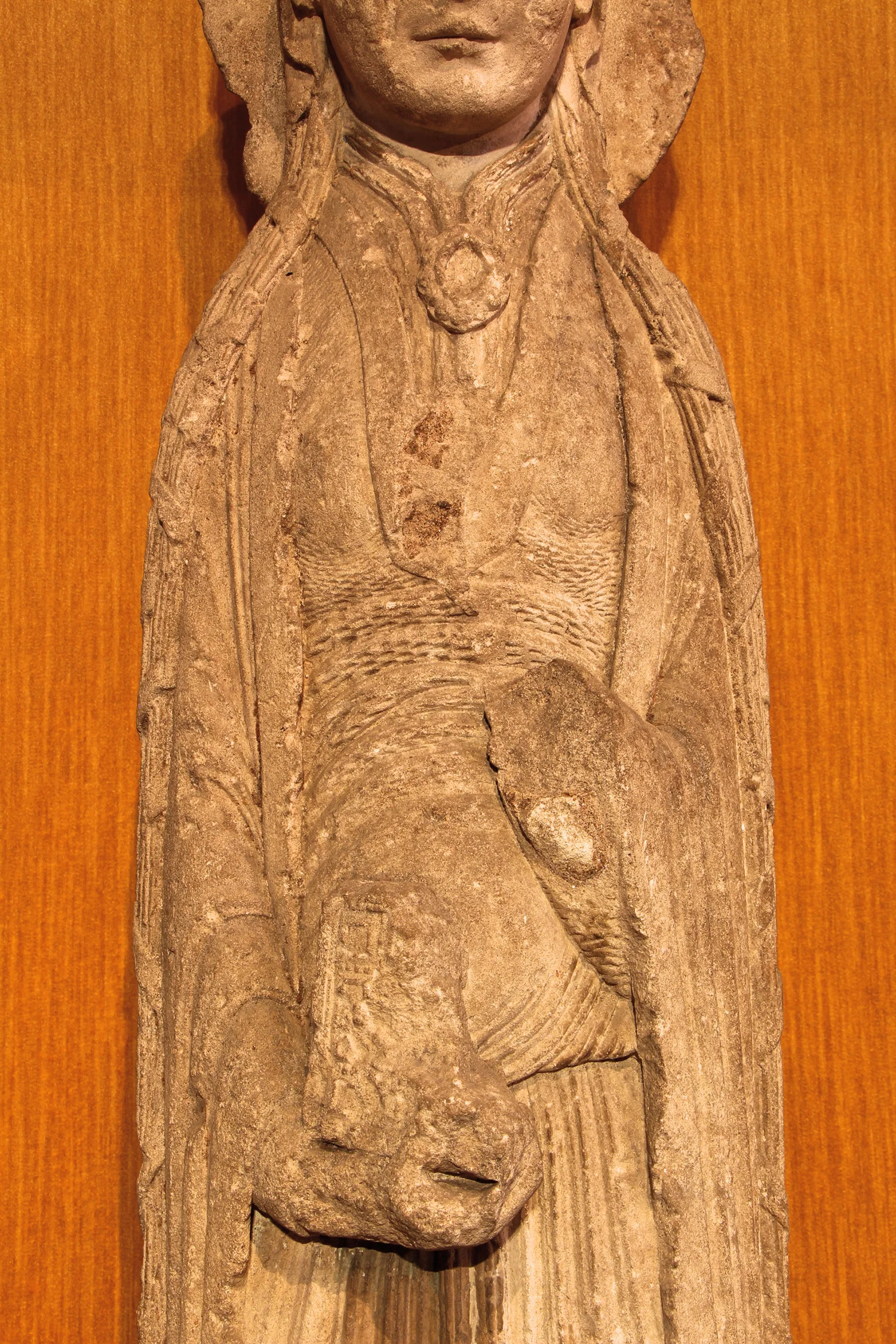 Figure 2: The woman depicted in the sculpture wears the garments of a highborn medieval lady. She holds the remains of a book in her hands.