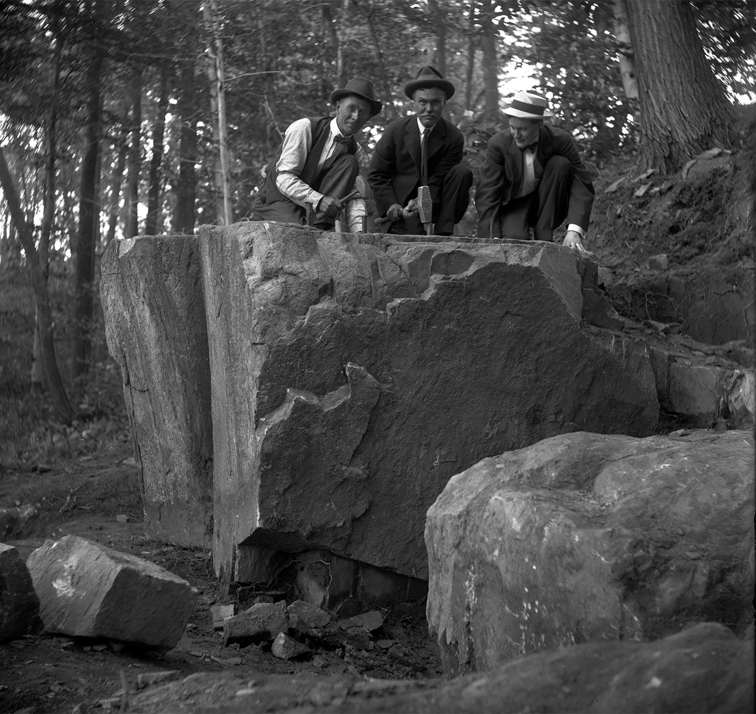 Figure 4: From left to right, Edward Kessel, Pringle Borthwick, and Raymond Pitcairn strike a pose with hammers and wedges in preparation for splitting the cornerstone from the boulder.