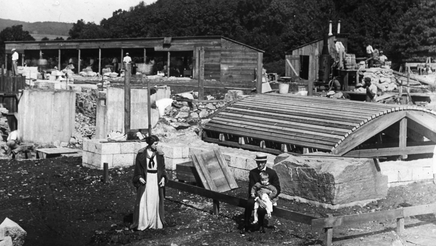 Figure 5: Mildred and Raymond Pitcairn visit the cornerstone with their son Nathan during the summer of 1914. The curved wooden structure in the photograph was a temporary frame used in the construction of an arched stone ceiling under the Cathedral's sanctuary.