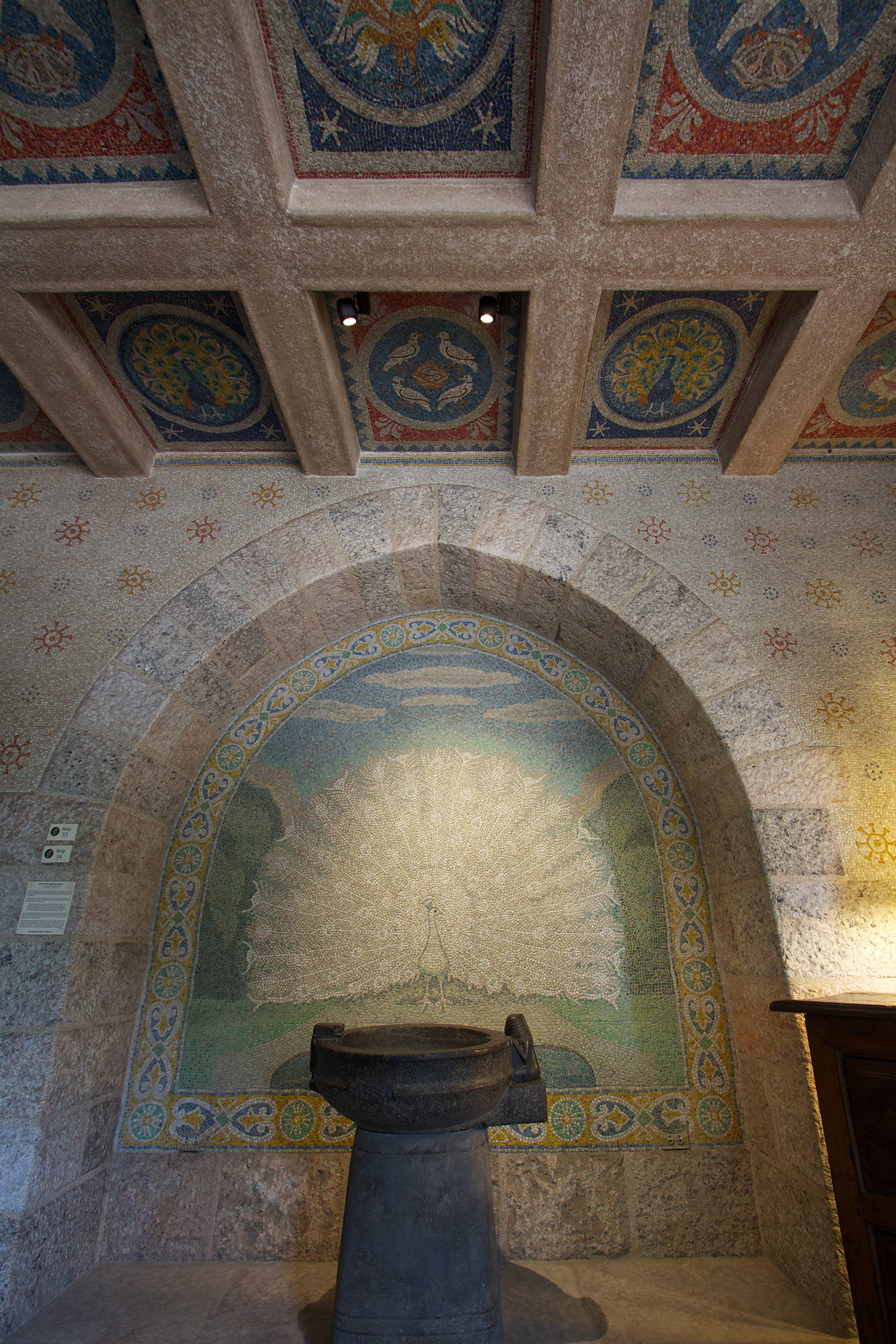Figure 5: Various types of mosaic birds decorate the Bird Room ceiling and a white mosaic peacock provides a backdrop for an ancient Egyptian libation bowl.