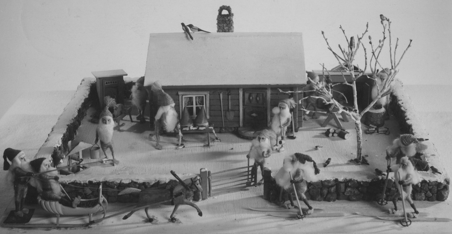 Figure 6: Tomtelandskap postcard mailed as a Christmas greeting in 1948. The figures, tools, expressions, activities, and style are remarkably similar to Glencairn's example. In particular, note the tomte smoking a pipe near the front door and compare him to the one in Glencairn's scene (Figure 1). 