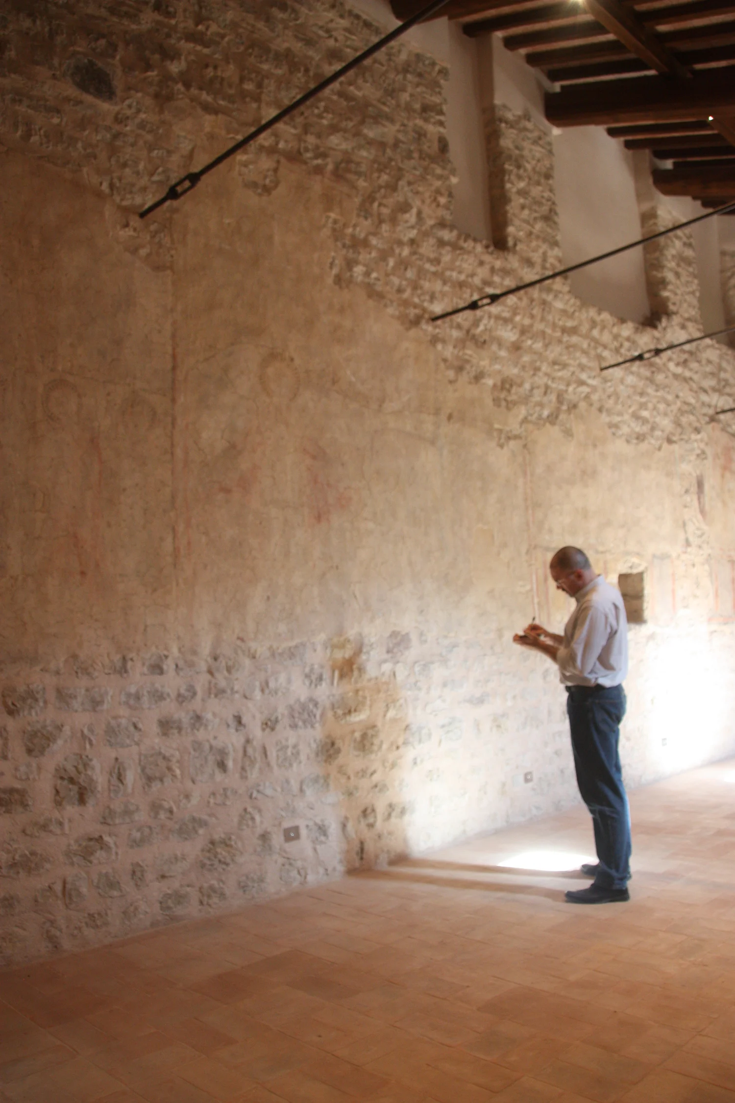Figure 13. The author in the monastery of Santa Maria inter Angelos, facing the section of the north wall where the Second Coming fresco was originally located. Faint traces of pigment are visible in the preparatory plaster remaining on the wall, as are slight depressions that gave texture to the halo of Mary. Photograph by Caroline Kline.