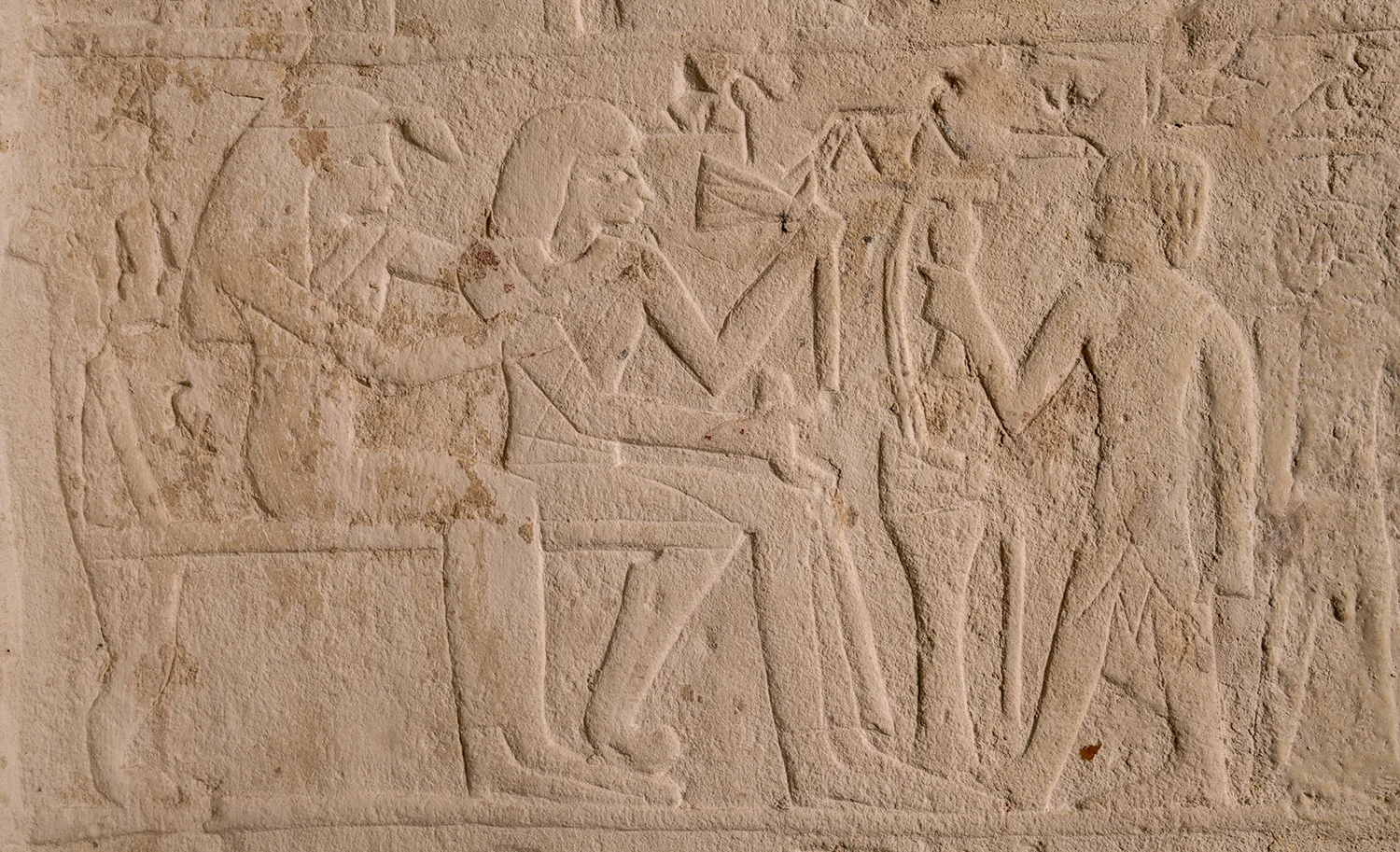 Figure 27: A detail from the stela of Maienhekau showing the deceased and his wife seated on chairs. In front of them, a son makes an offering to the couple.