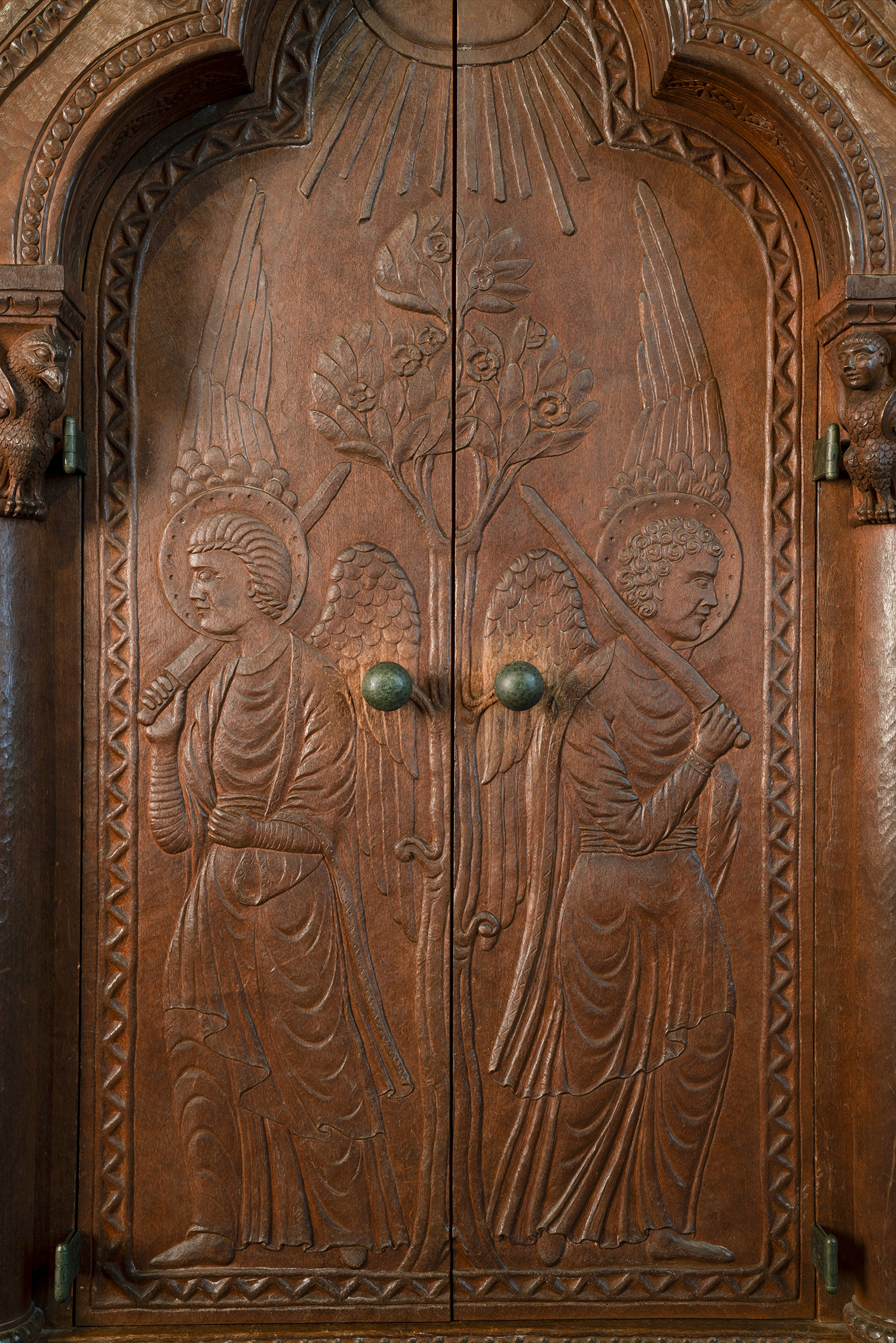 Figure 7: Angels with flaming swords stand guard at the entrance to the garden of Eden (Genesis 3:24). The door pulls emerge from a tree as if they are pieces of fruit.
