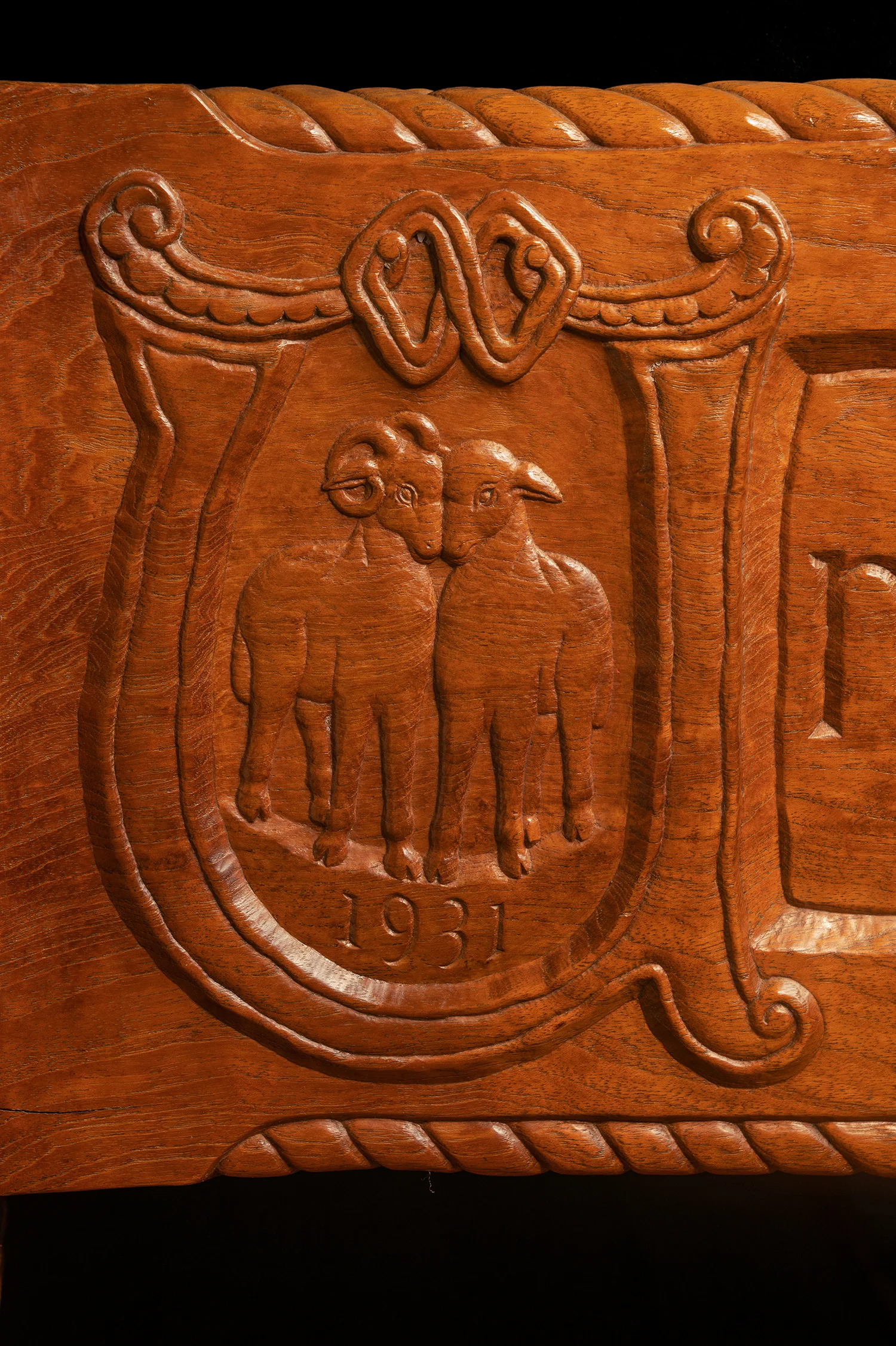 Figure 17: A quotation taken from the wedding ceremony of Raymond and Mildred Pitcairn is carved around three sides of the base of their bed. Here a ram and ewe, a symbol for husband and wife, are enclosed by the initial letter “U” beginning the quotation. The date of the bed’s completion—1931—is incised below the ram and ewe.