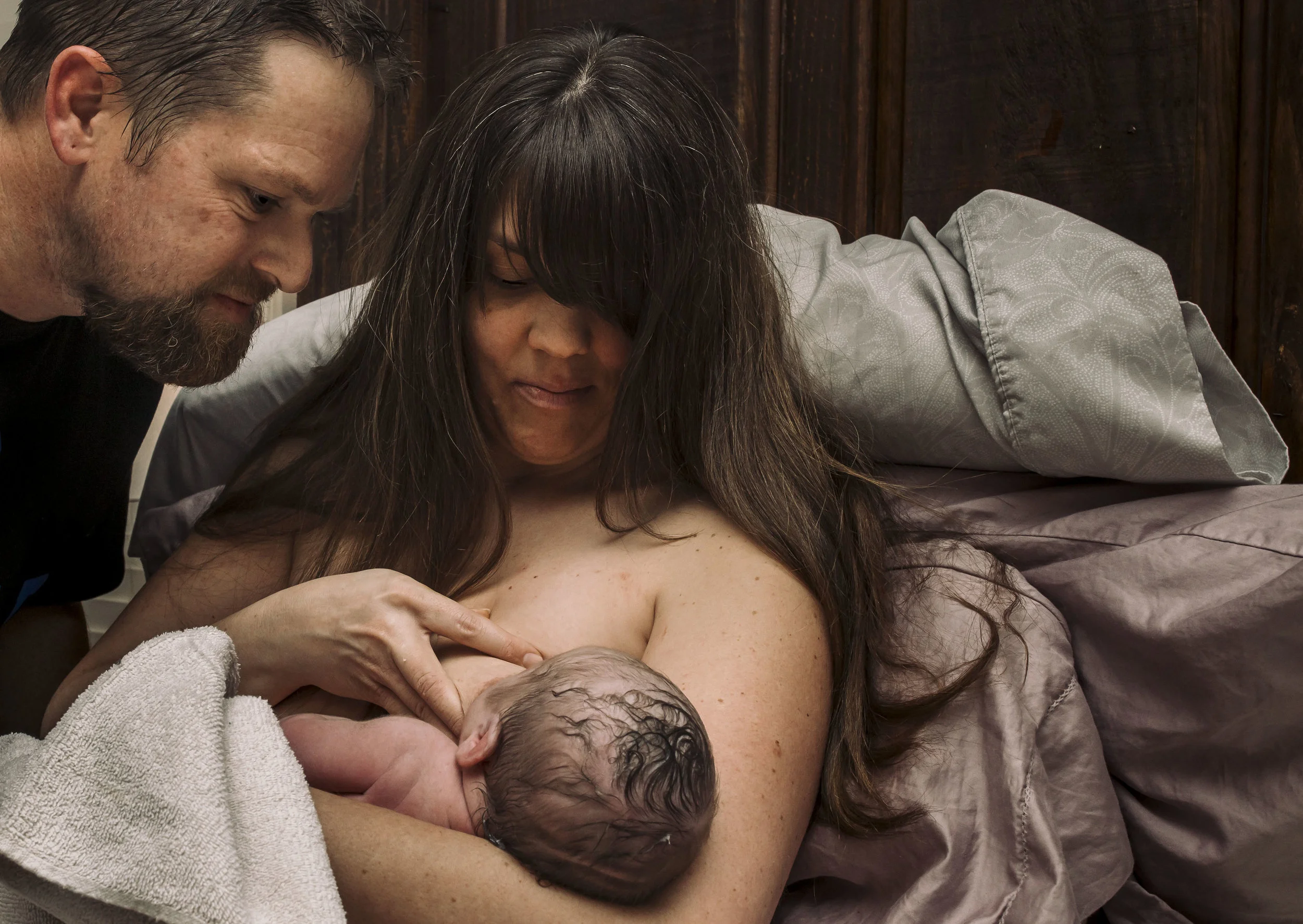 mom and dad looking at new baby at home birth