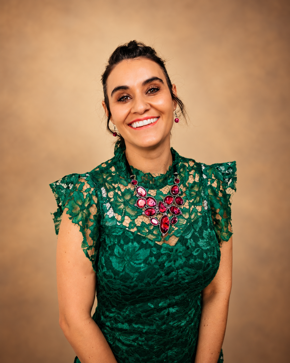 Kat, founder of Body Sugar Boutique, wearing an emerald green dress against a warm amber backdrop