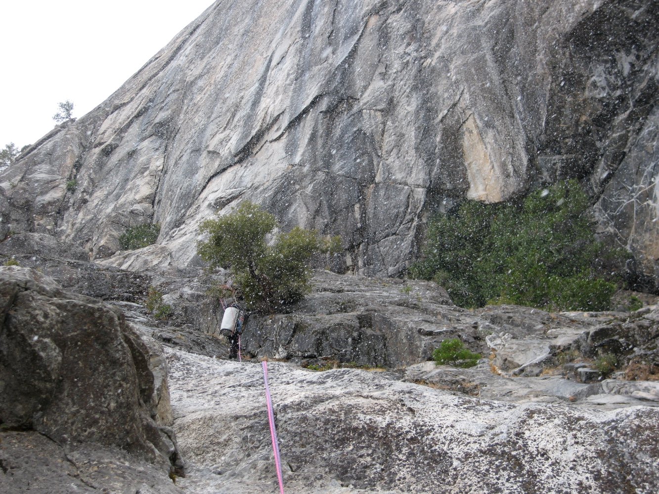Gemma abseils with a haul bag during snow showers