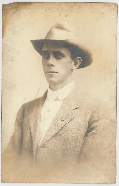Black and white vintage photograph of a young man wearing a suit and a wide-brimmed hat.