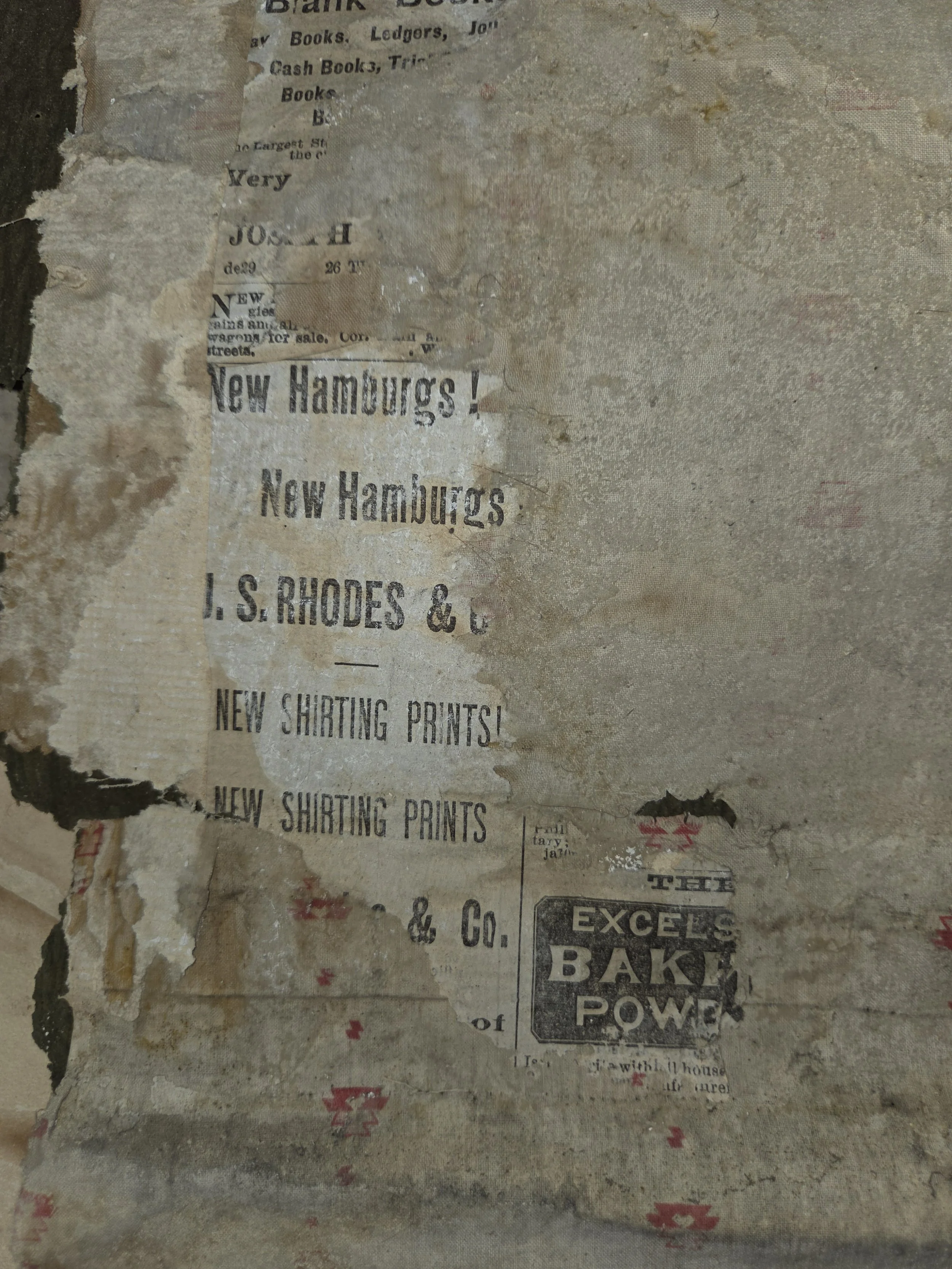 Old, torn paper with faded print advertising for new Hamburgers, shirt printing, and baking power, on a weathered wall.