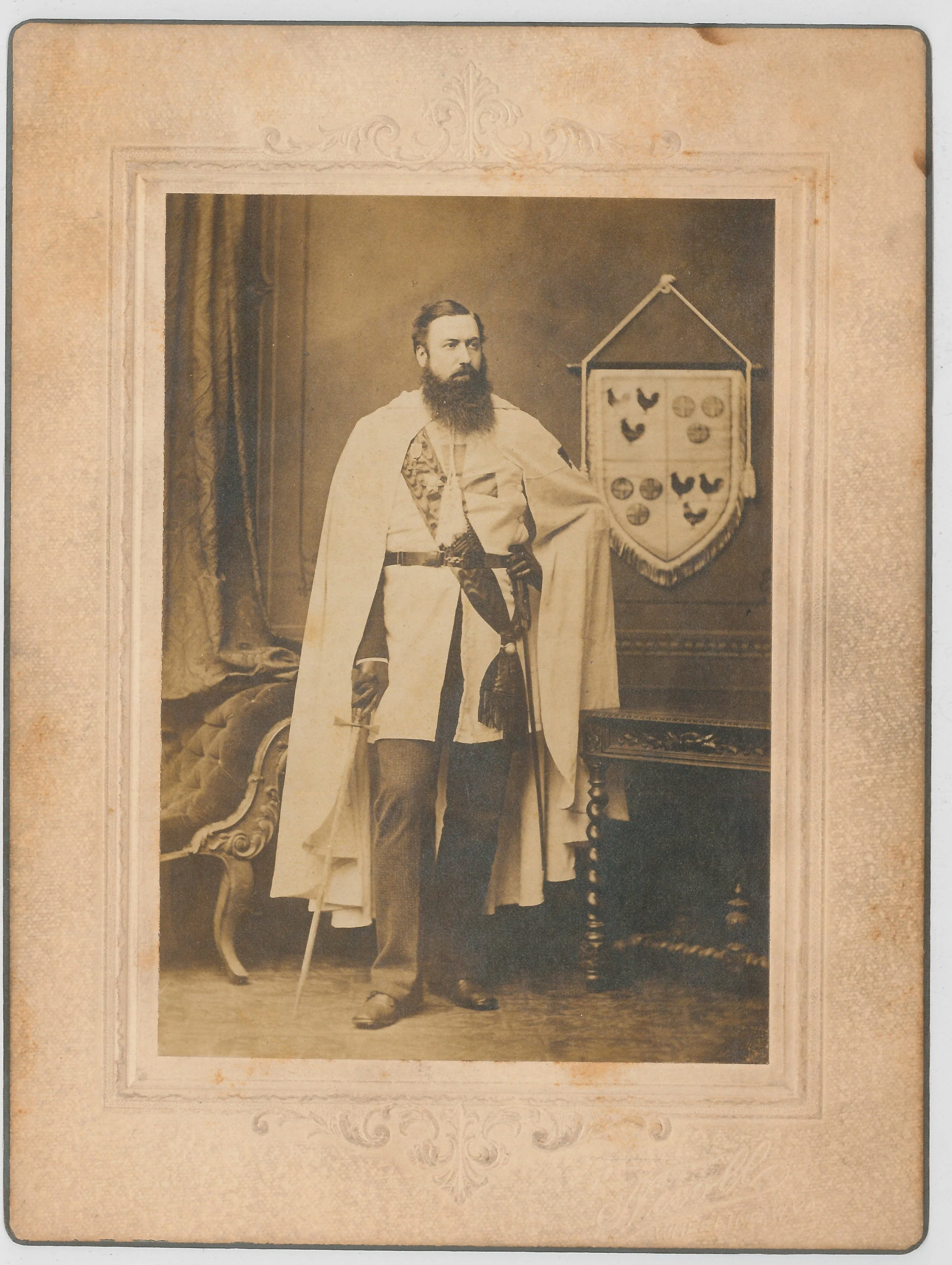 Andreas Edmund Cockayne standing next to a banner of the family crest.