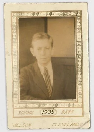 A sepia-toned vintage photograph of a young boy in a suit and tie, placed inside a decorative frame with the text 'School 1935 Days' and the name 'Willson Cleveland' written at the bottom.