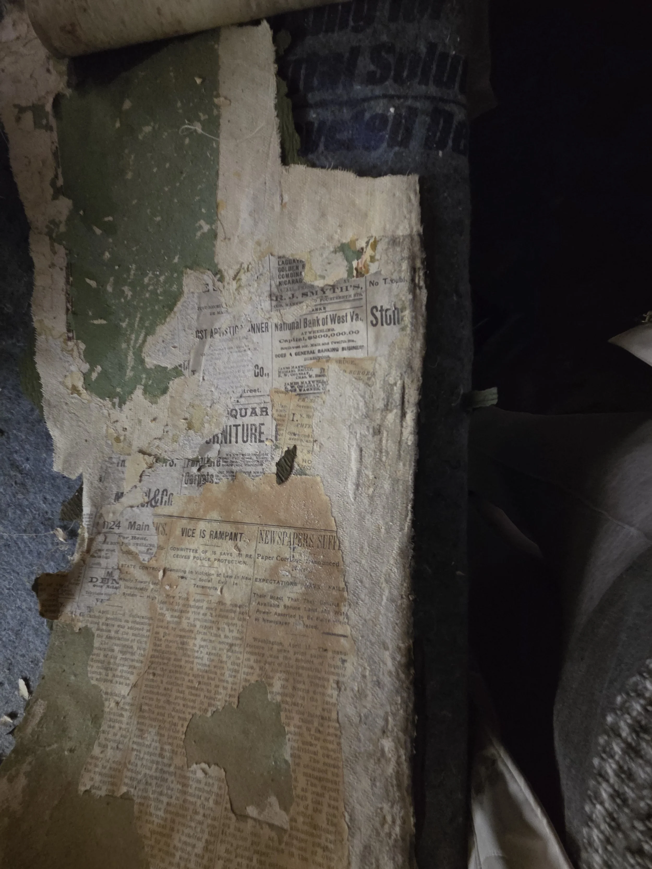 Old, torn newspaper clippings stuck to a worn, peeling wall with chipped paint.