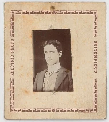 Black and white photo of a young man with dark hair, wearing a suit and tie, in an old-fashioned portrait style.