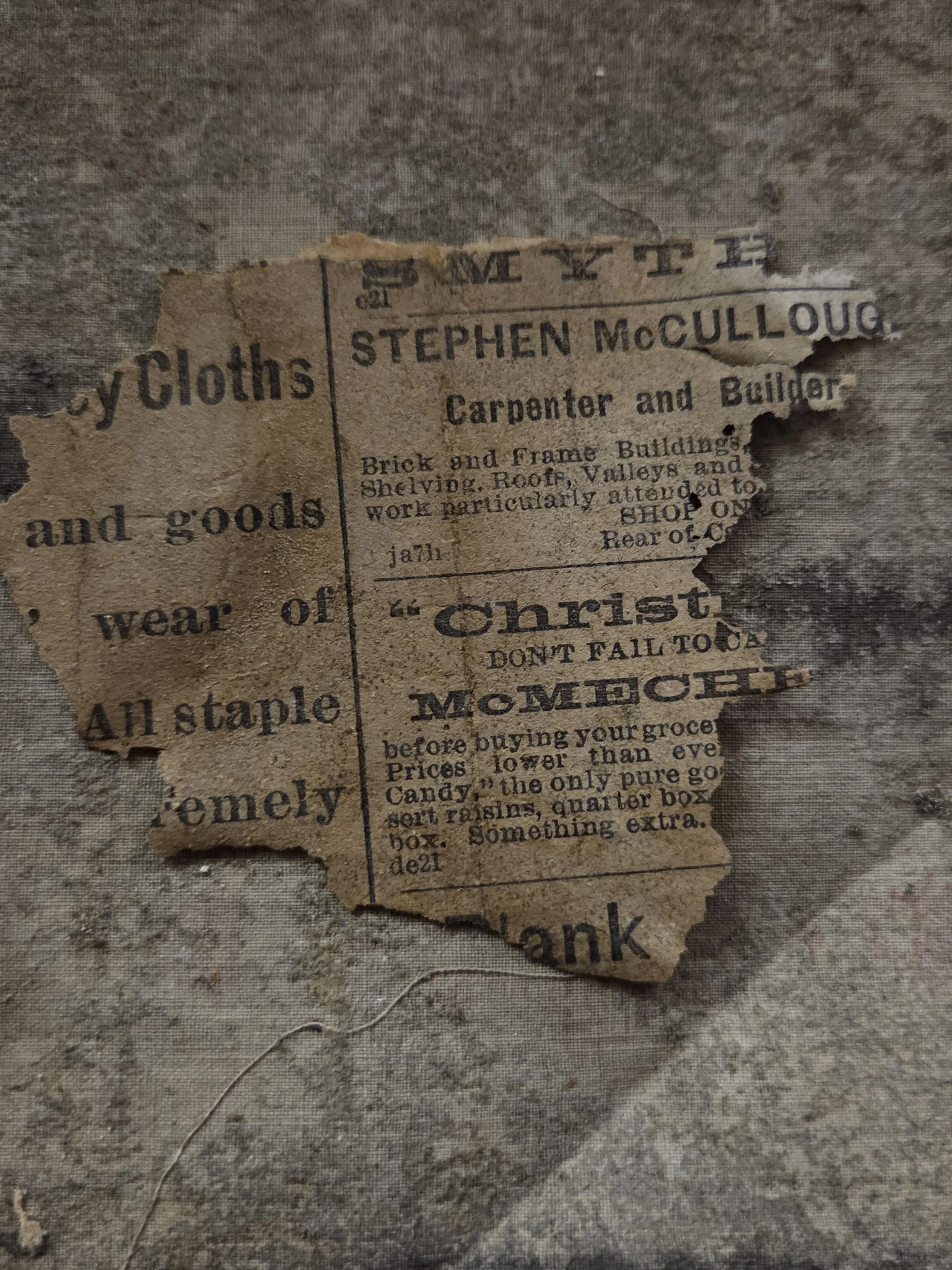 A torn, old paper advertisement for fabric and tools, featuring the name Stephen McCullough, a carpenter and builder, with text about brick and frame buildings, and a mention of Christmas.