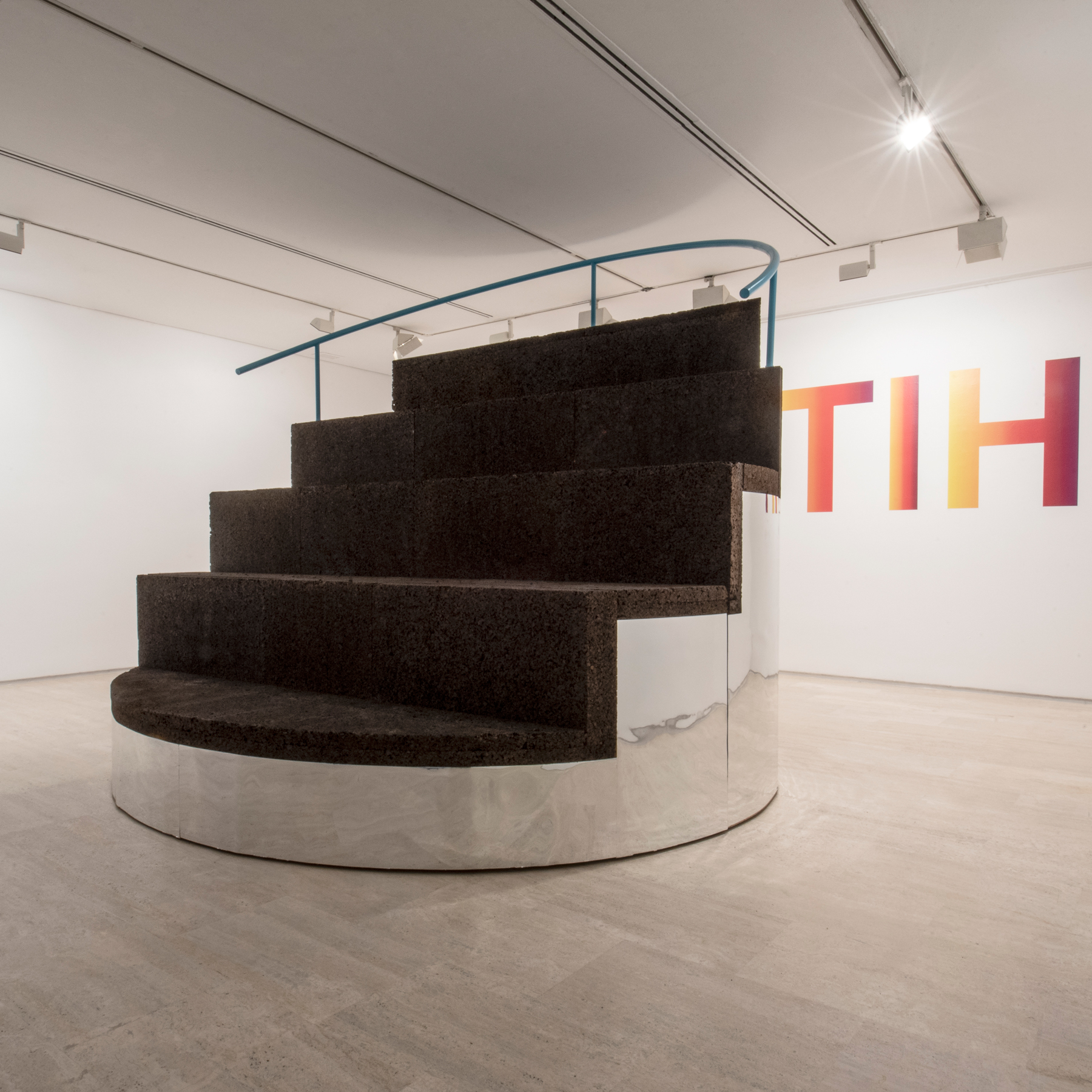 Stairway to hitzak es un dispositivo lúdico-pedagógico capaz de equipar y al mismo tiempo resignificar el espacio donde se inserta. Está diseñado para facilitar y promover el intercambio y generación de nuevo conocimiento especialmente entre niños y familias diversas. Para ello se compone de varias capas y estrategias de interacción, a través de su capacidad transformable: En su posición cerrada es una gran grada colectiva donde los visitantes de Koldo Mitxelena tienen un espacio de uso espontáneo, donde hacer un alto en el camino, charlar con otros, escalar, jugar, leer o ver la proyección de un documental. Se plantea como un prototipo a microescala con la intención de testear nuevas maneras de usar los espacios de la futura e innovadora biblioteca, potenciando la interacción y la relación lúdica e intelectual entre los futuros usuarios del espacio. En la sala aparece como un volumen suave, sinuoso, sin esquinas, sin lados principales o secundarios, sin ángulos pronunciados. Se trata de un cilindro perfecto, un volumen de espejo tridimensional que refleja y proyecta todo lo que tiene en su entorno próximo, desdibujando la base de la grada colectiva fabricada en corcho, y generando un efecto casi de escalera flotante hacia el cielo o en nuestro caso “a la palabra”, tal y como Led Zeppelin tituló sus ocho minutos de obra maestra “Stairway to heaven”. Al igual que la obra musical, el dispositivo tiene la capacidad de desplegarse y descomponer en tres piezas compositivas únicas y equipada, proporcionando los elementos básicos de trabajo que Koldo Mitxelena necesita para desarrollar workshops creativos, encuentros espontáneos o actividades pedagógicas programadas, construyendo el contexto necesario para re-descubrir de manera colectiva el papel de la palabra en nuestro futuro más próximo. “There’s a lady who’s sure all that glitters is gold / and she’s buying a stairway to heaven When she gets there she knows, if the stores are all closed With a word she can get what she came for.” “Hay una dama que está convencida de que todo lo que brilla es oro y está comprando una escalera al cielo. Cuando llega allí, sabe que si todas las tiendas están cerradas con una palabra ella puede conseguir lo que vino a buscar”