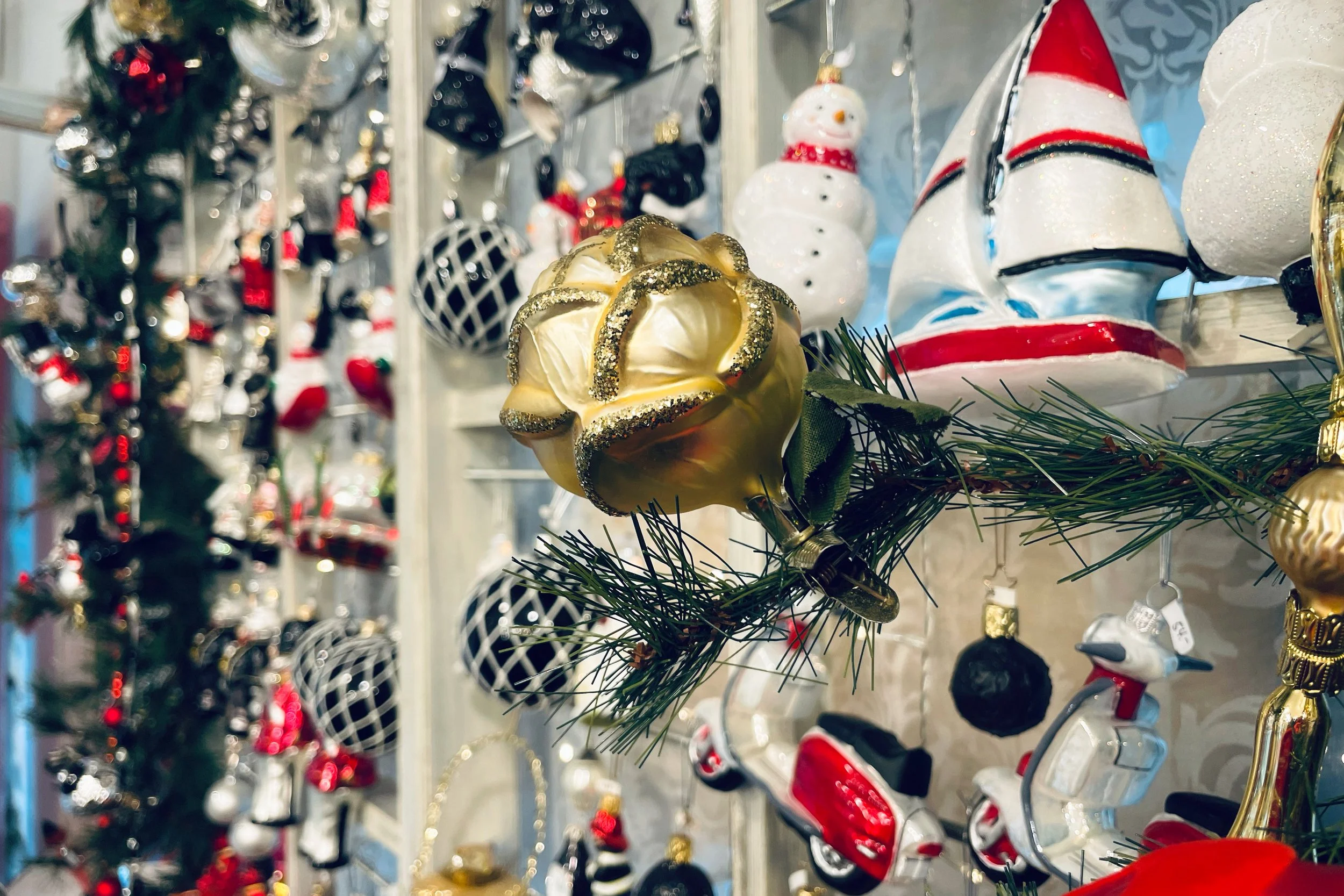 Szenenbild aus dem Pegasus von auserlesenen, mundgeblasenen Glas Weihnachtskugeln und Weihanchtsformen. Segelschiff, Vespa, Schneemann, Pilze, Rosen auf Klammern oder Pralinen sind zu entdecken. 