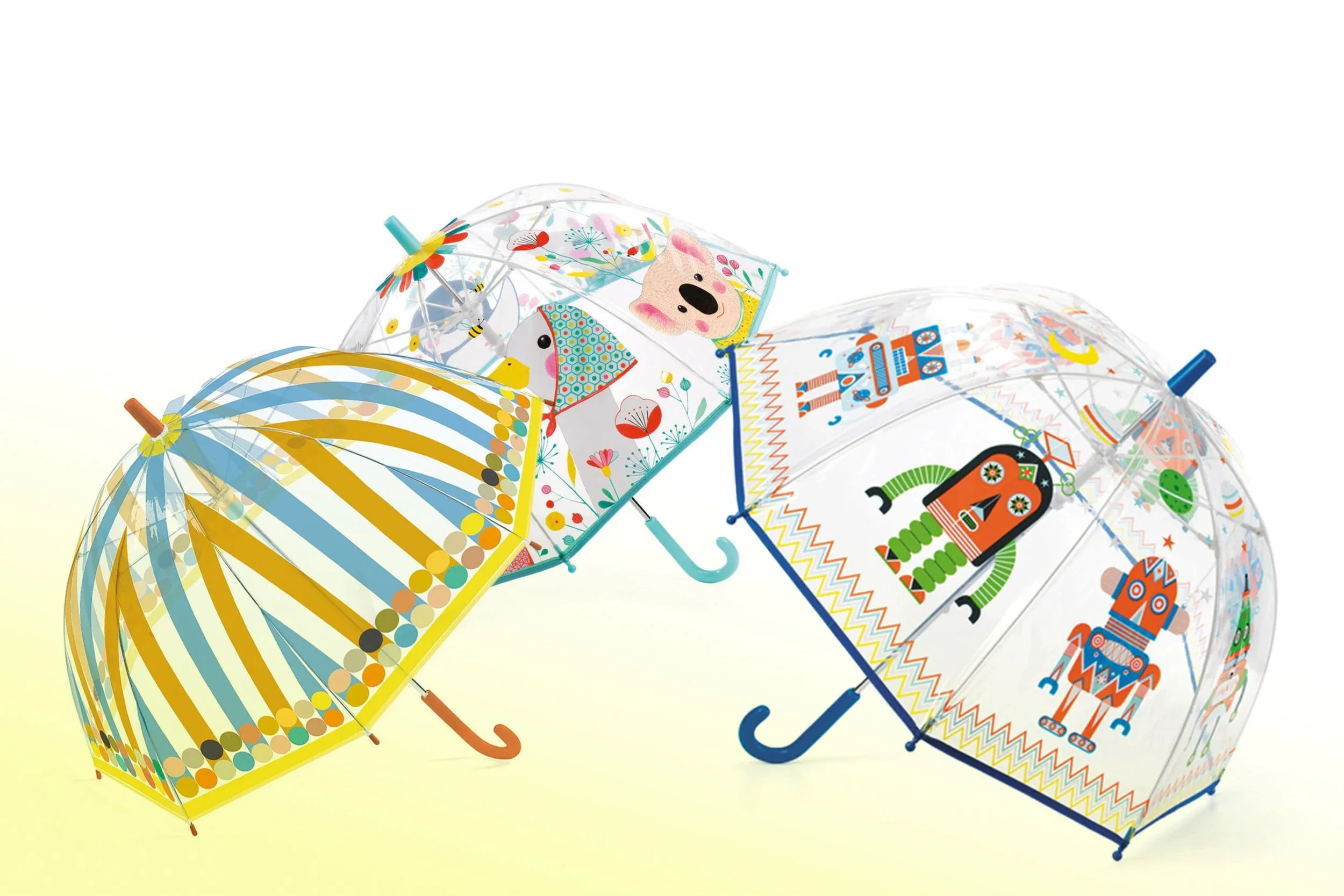 Drei transparente Regenschirme der Marke Djeco mit bunten, kindgerechten Motiven. Der erste Schirm hat gelb-blau gestreiftes Muster. Der zweite Schirm zeigt bunte Tiere und Pflanzen. Der dritte Schirm hat ein robotisches Design mit Robotermotiven.
