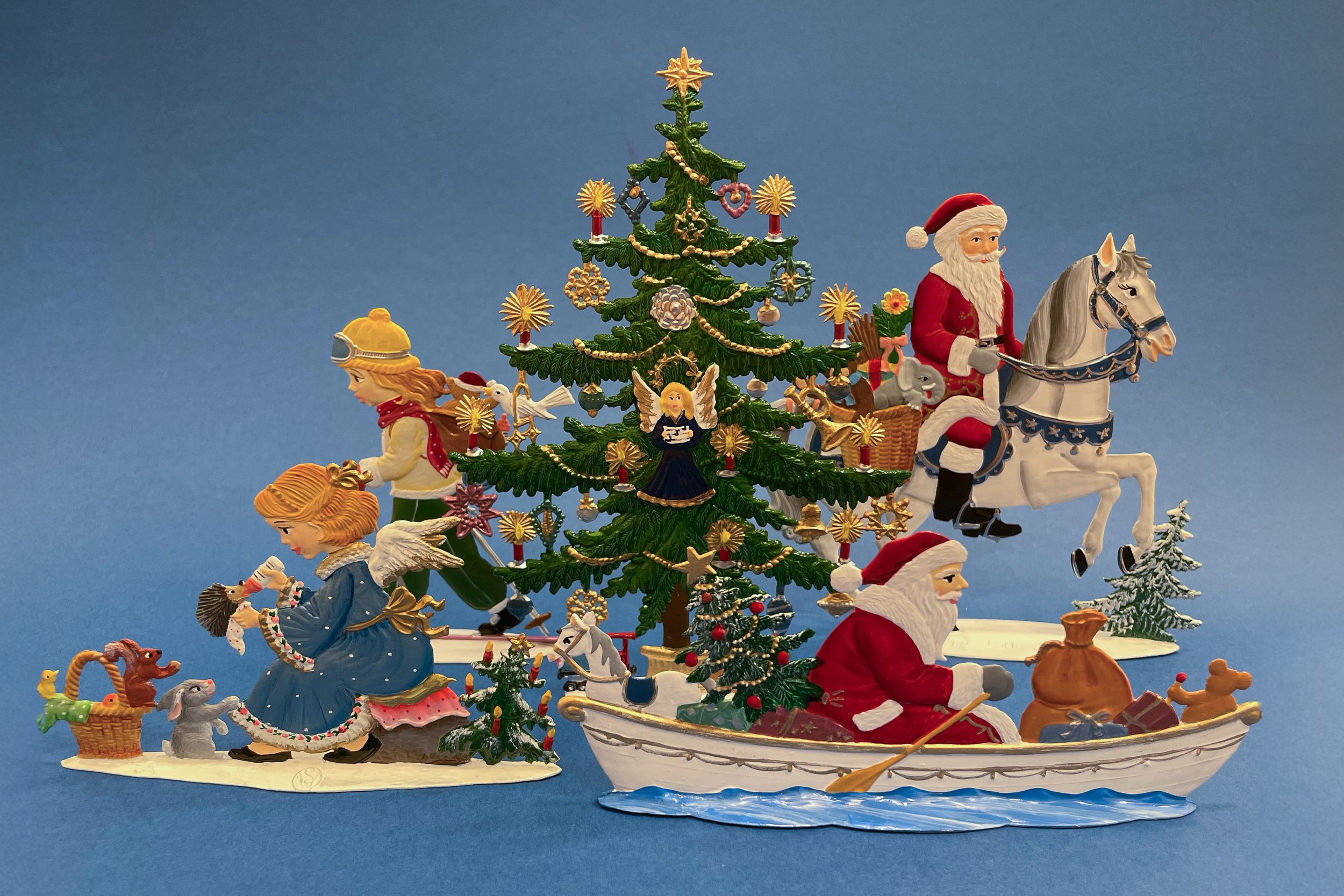Figuren aus der Wilhelm Schweizer Zinnmanufaktur: Nikolaus im Schiff und hoch zu Ross. Ein Engel mit Waldtieren, ein Mädchen auf Skiern, dazwischen ein Weihnachtsbaum.
