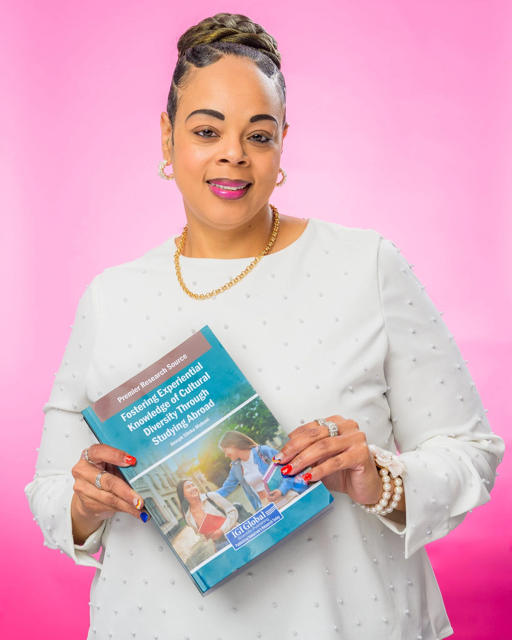 Personal branding portrait of a woman author holding a book against a pink studio background, photographed by Scott Photography in Richmond, VA.