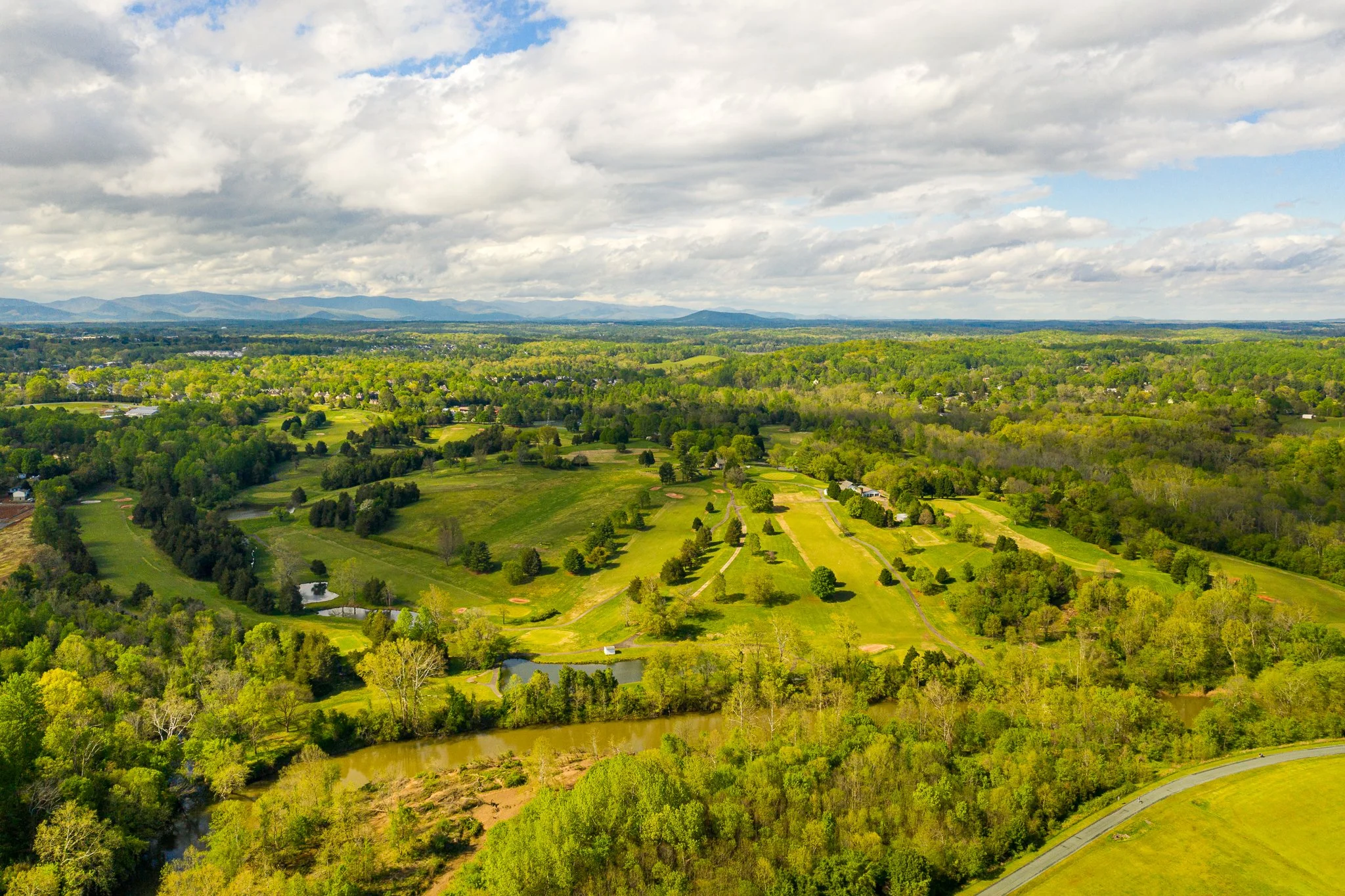 Aerial view of rolling green landscape and golf course in Virginia, photographed by drone to highlight natural terrain and land development.