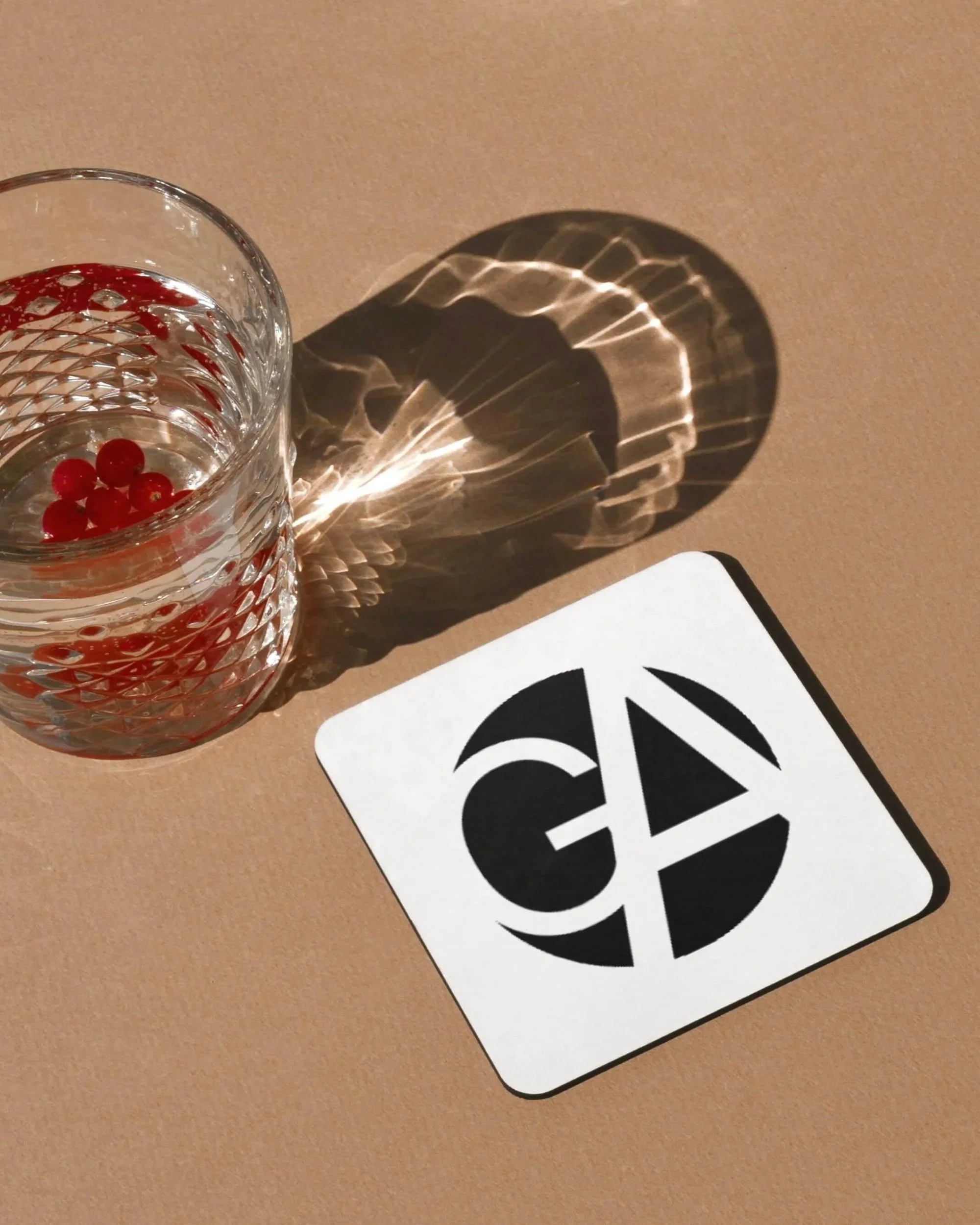 Bierdeckel mit Logo, daneben ein Glas