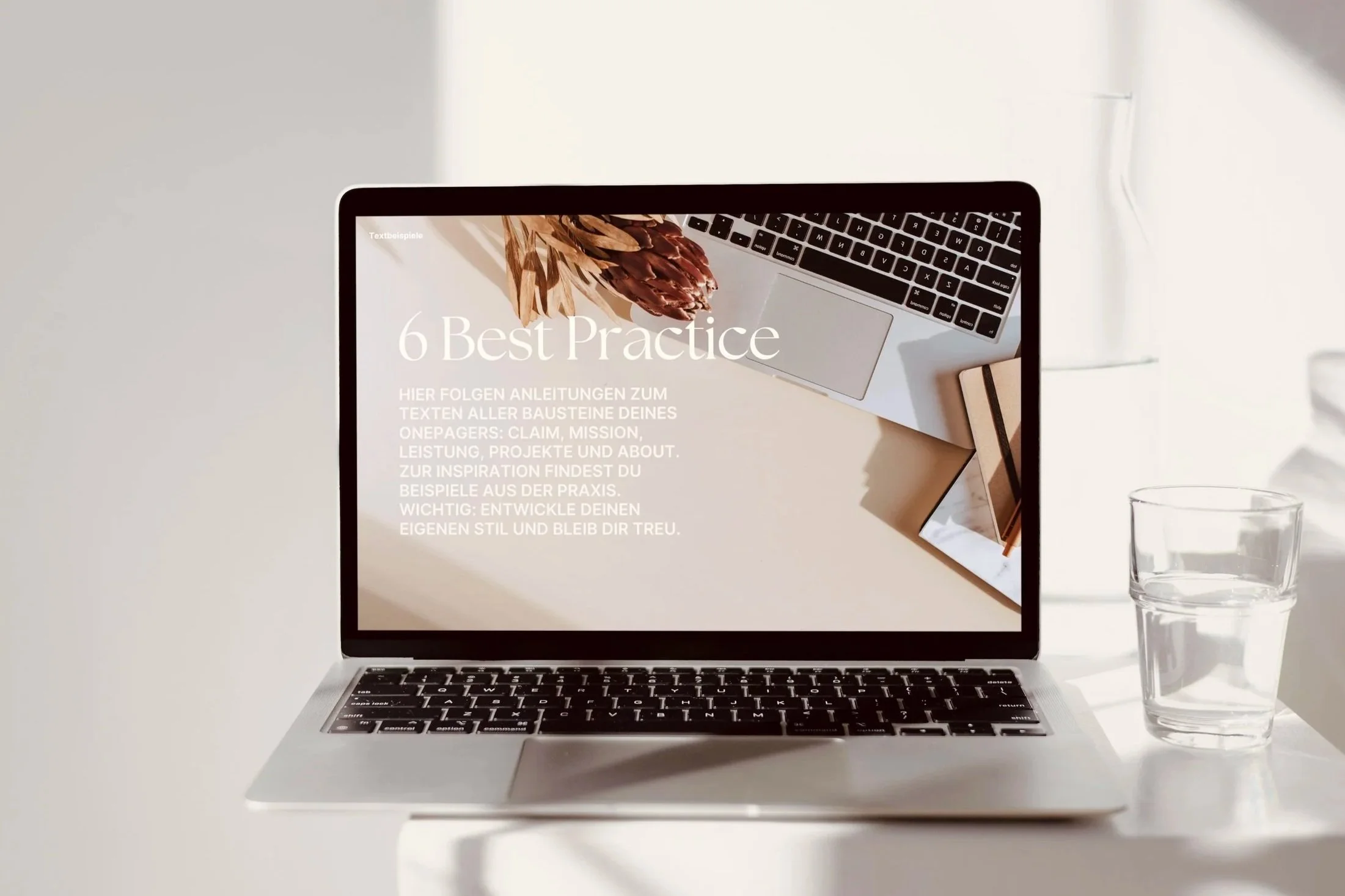 Macbook steht auf Podest vor weißer Wand, zeigt Website-Mock-up
