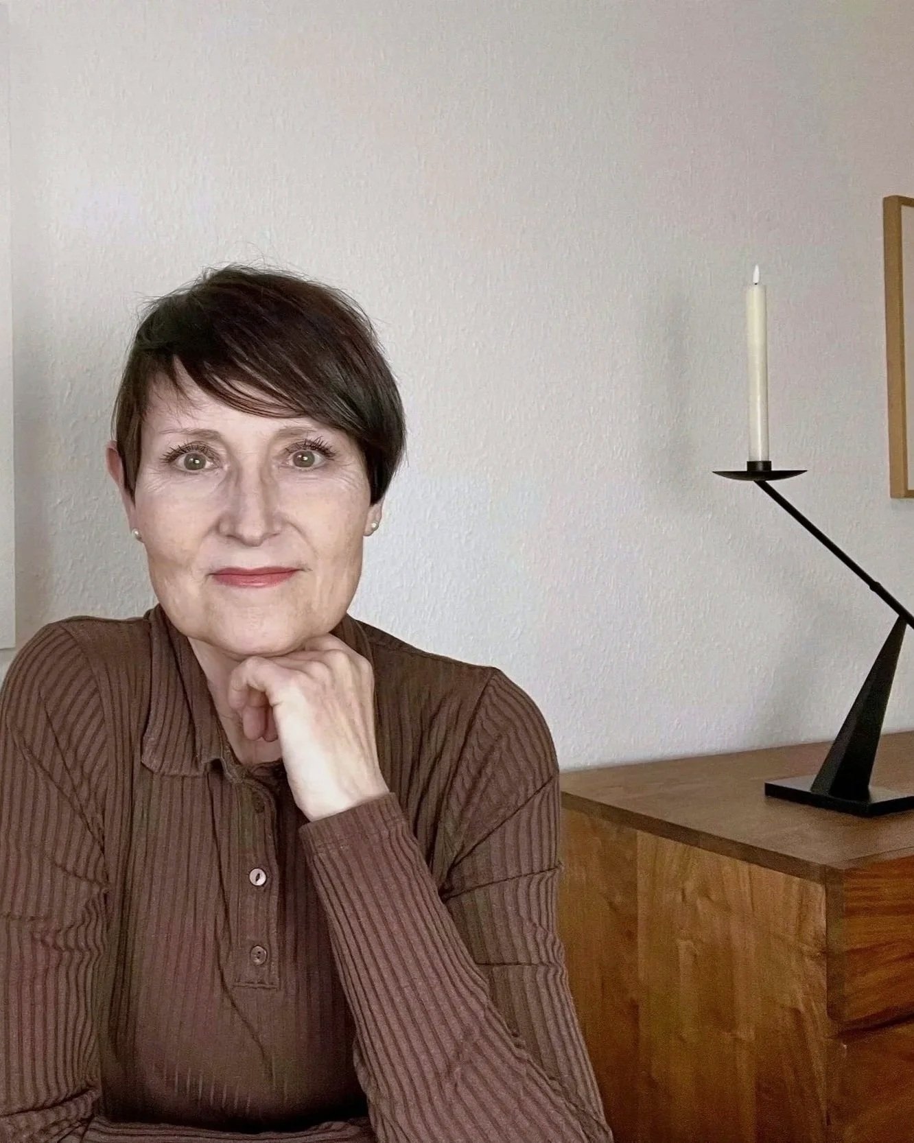 Frau mit dunklen kurzen haaren und brauen Polo-Shirt sitzt am Schreibtisch