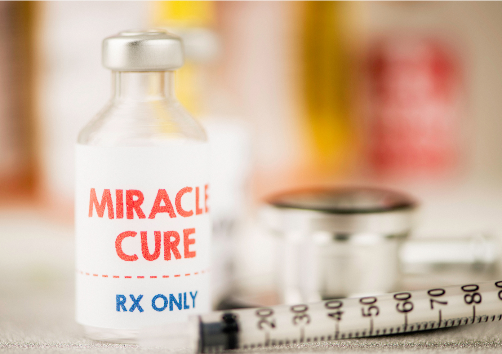 Fläschen mit roter und blauer Schrift (miracle cure), daneben Spritze