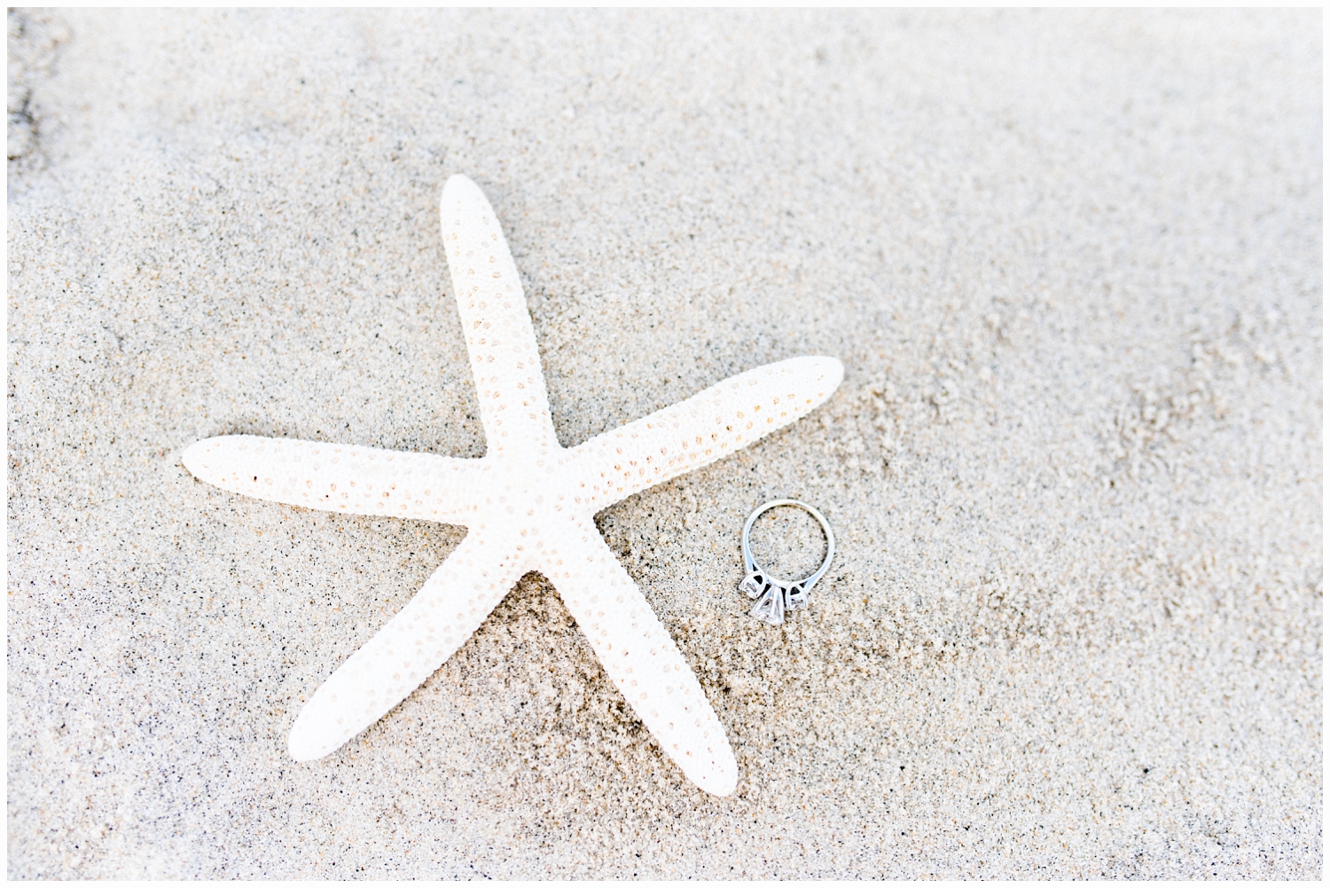 starfish in sand with engagement ring