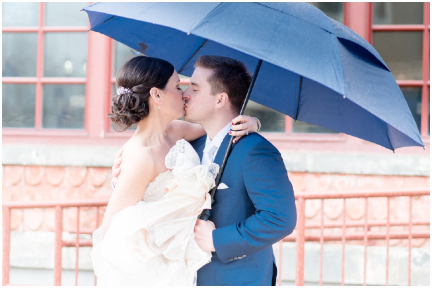 brida and groom kissing under umbrella