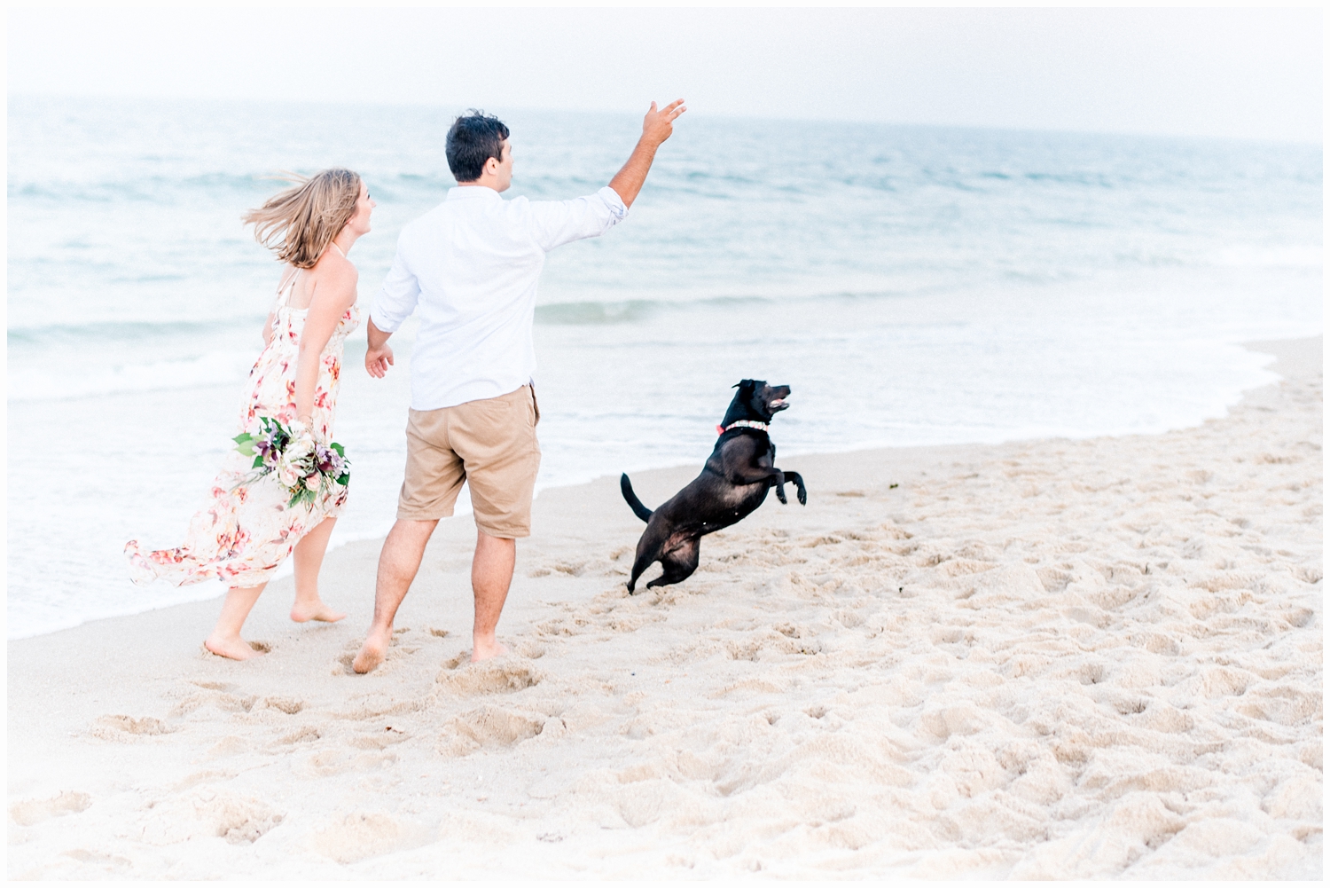 couple playing on beach with dog
