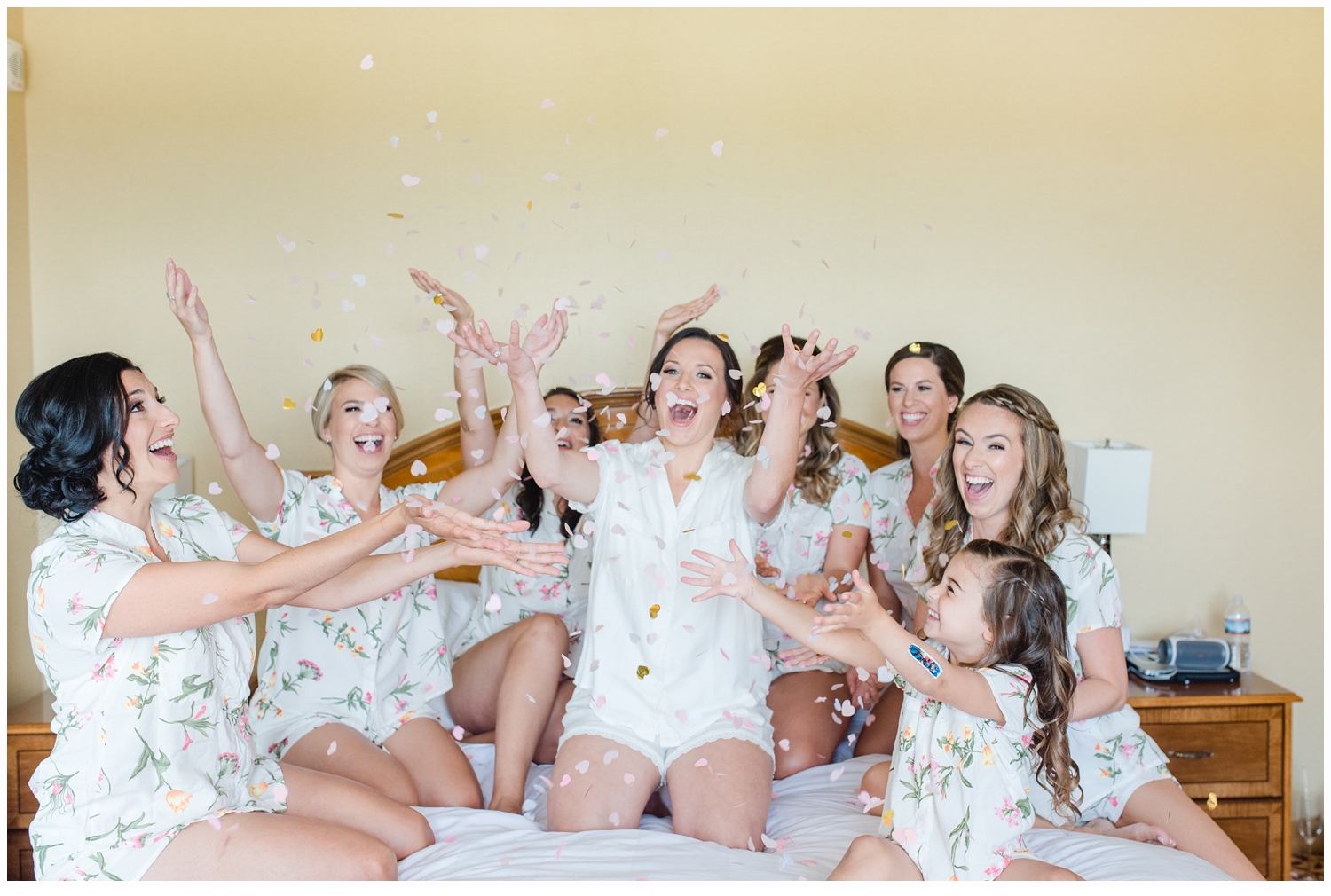 bride and bridesmaids throwing confetti on bed