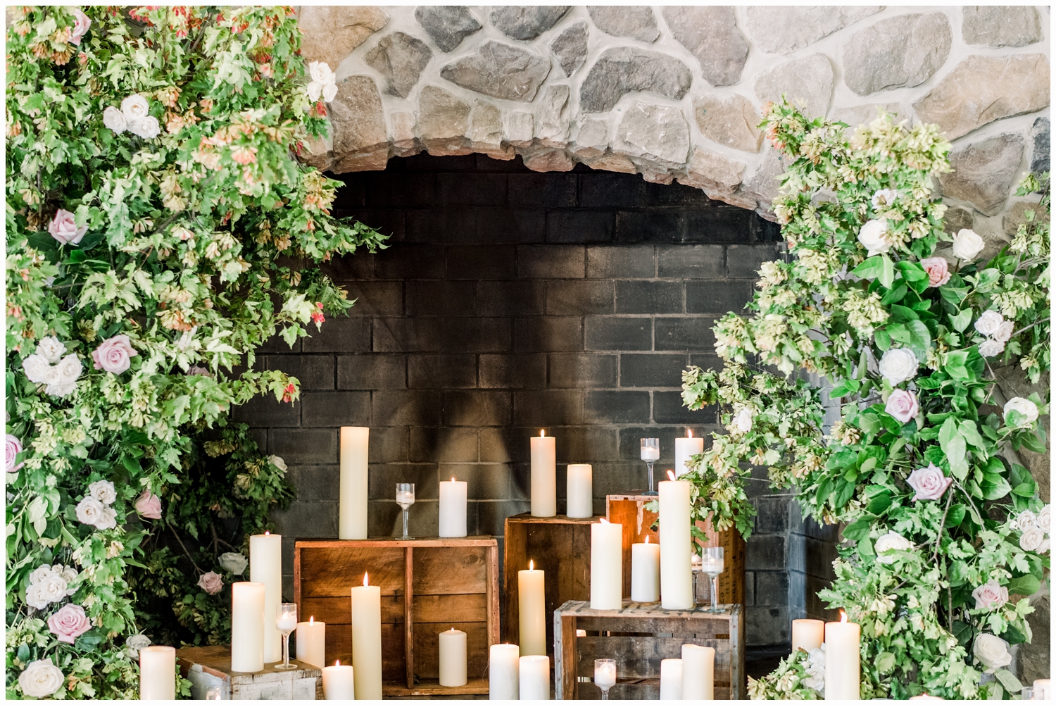 green florals and candles on a fireplace