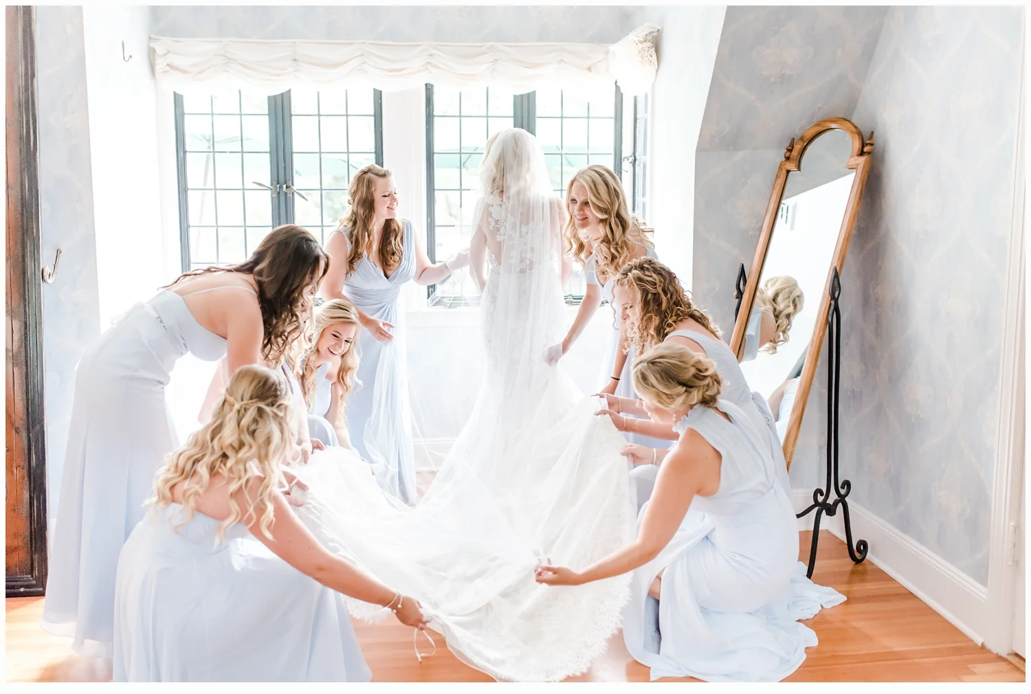 bridesmaids helping bride put on dress