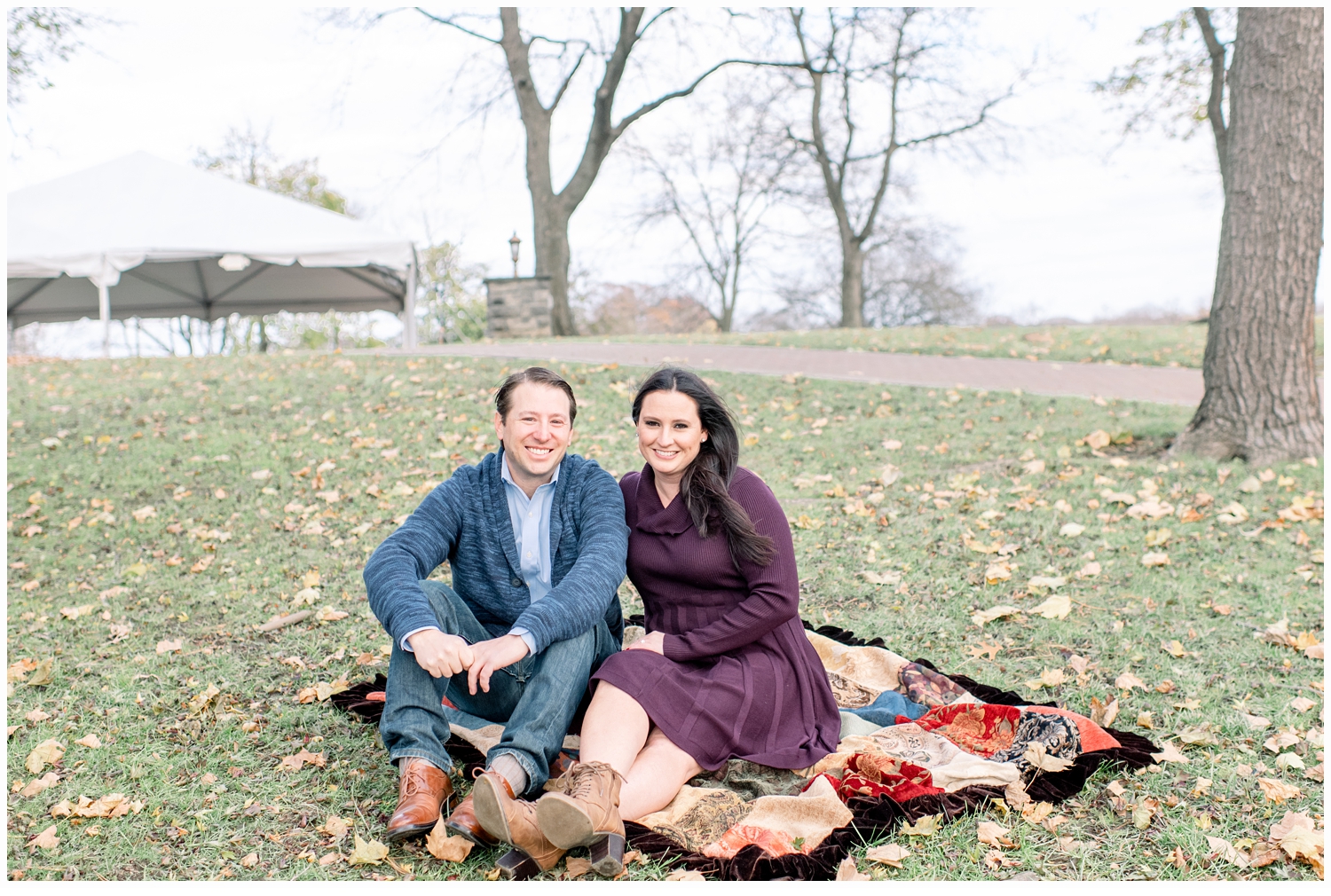 engaged couple sitting on a blanket in the grass