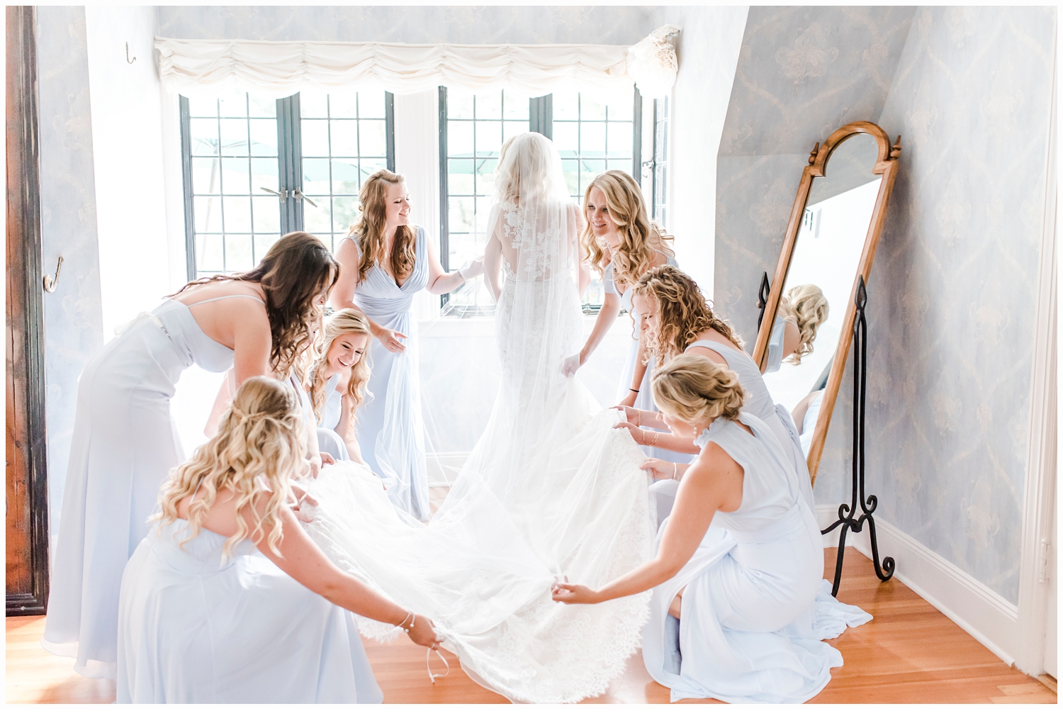 bridesmaids helping bride put on wedding gown