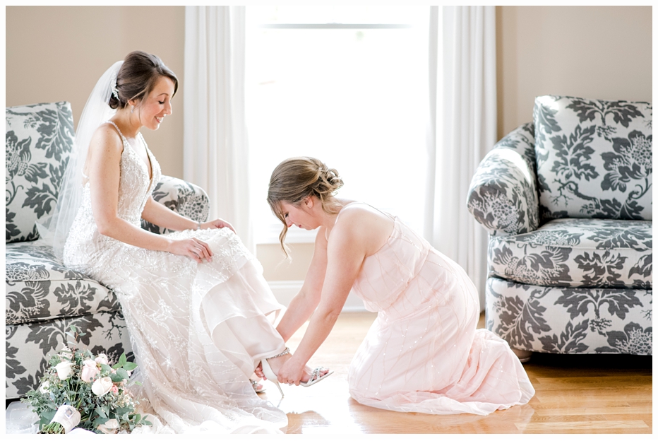 bridesmaid putting on brides shoes