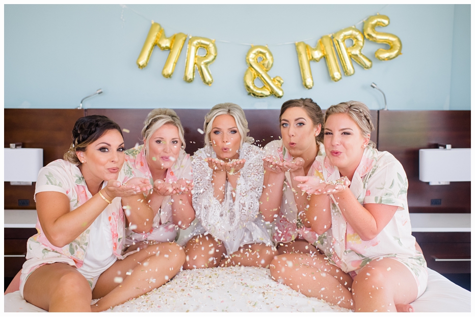 bride and bridesmaids blowing confetti in the air