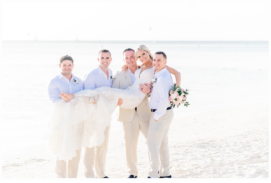 groom and groomsmen holding bride