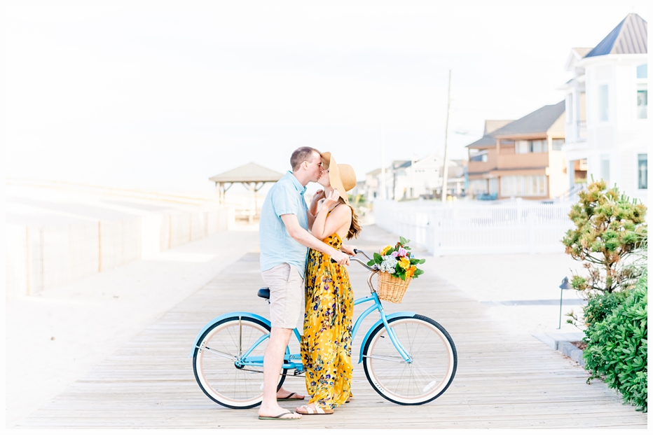engaged man and woman on a pretty beach bicycle kissing