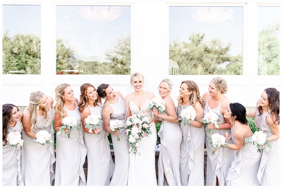 bride and bridesmaids laughing together wearing pretty grey dresses
