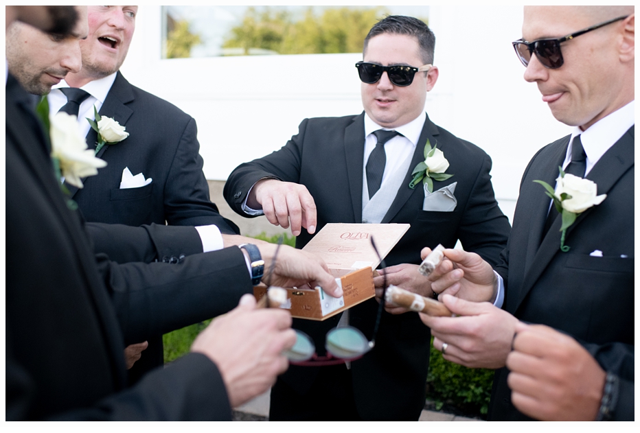 groom and groomsmen sharing a box of cigars
