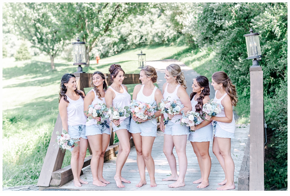 bride and bridesmaids carrying pretty bouquet on a bridge