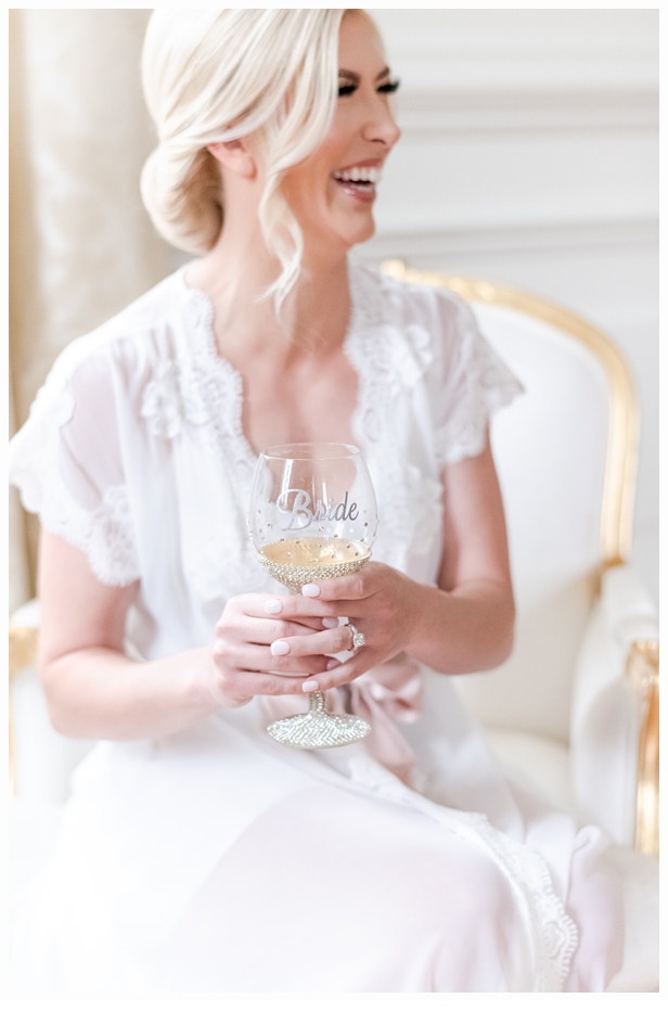 bride in pretty white robe drinking champagne
