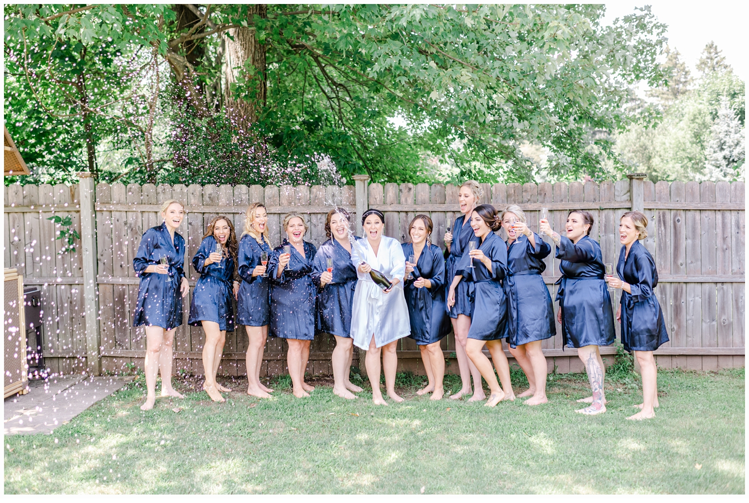 bride and bridesmaids in blue silk robes opening a bottle of champagne