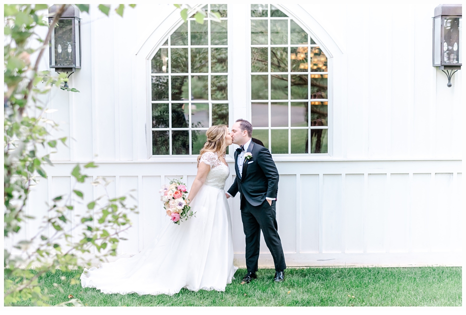bride and groom kissing in front of a pretty white window
