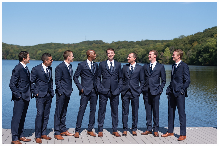 groom and groomsmen on a dock on a lake